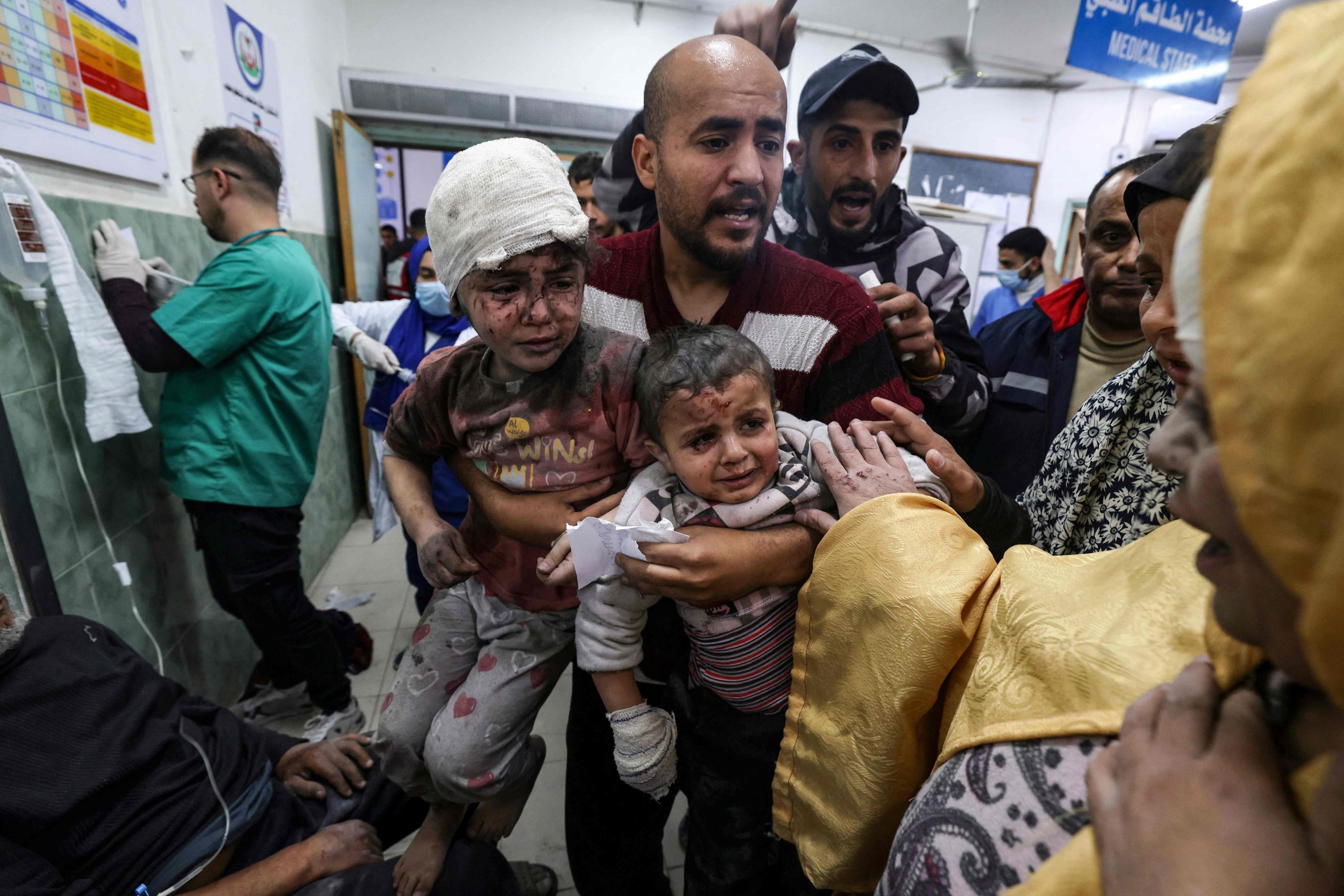 A man in a Gaza Strip hospital in March 2024 carries two children injured during an Israeli bombardment. Photo: AFP