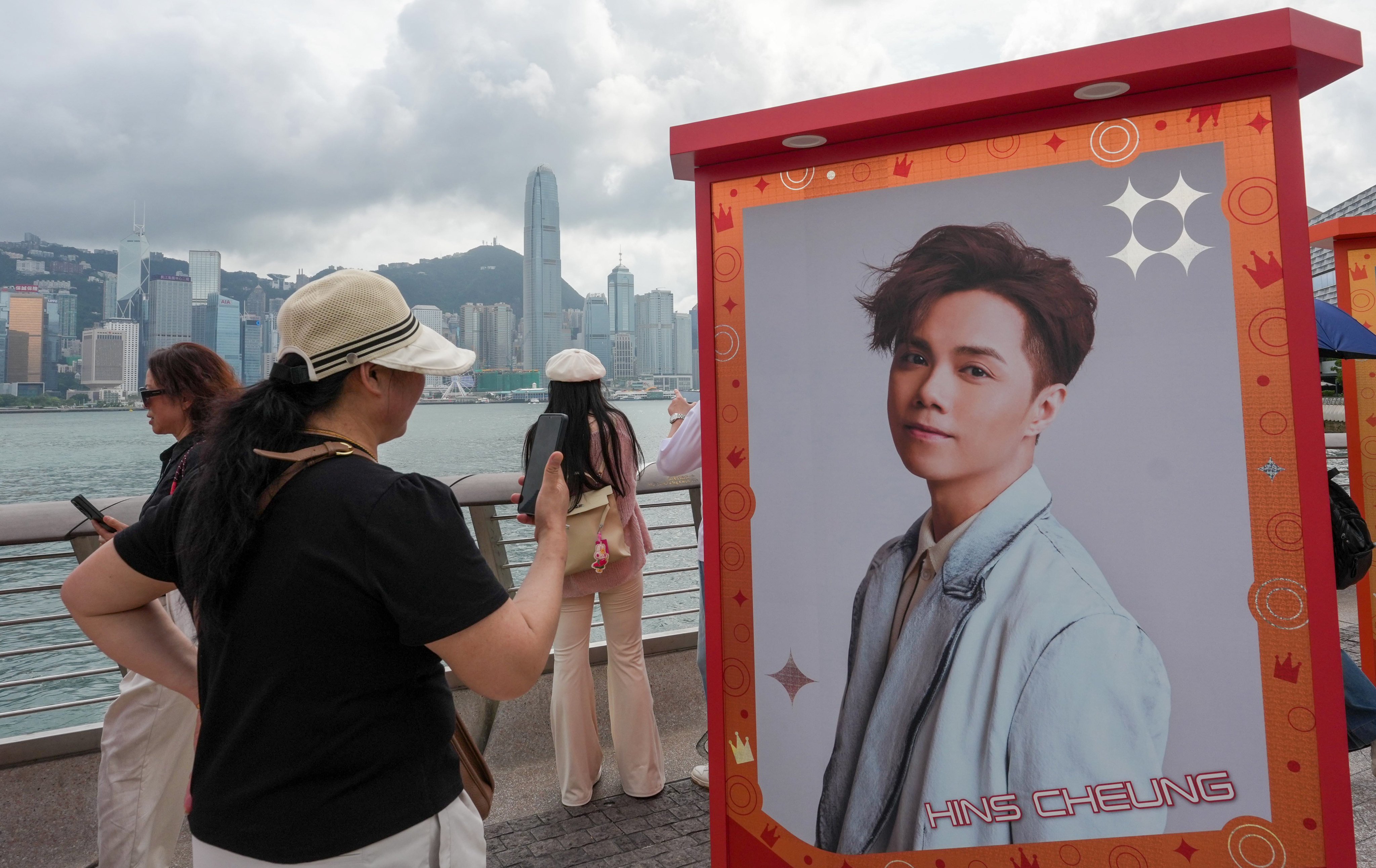 A woman takes a picture of a giant poster of Hins Cheung on the Tsim Sha Tsui waterfront promoting a concert, in April this year. Photo: Jelly Tse