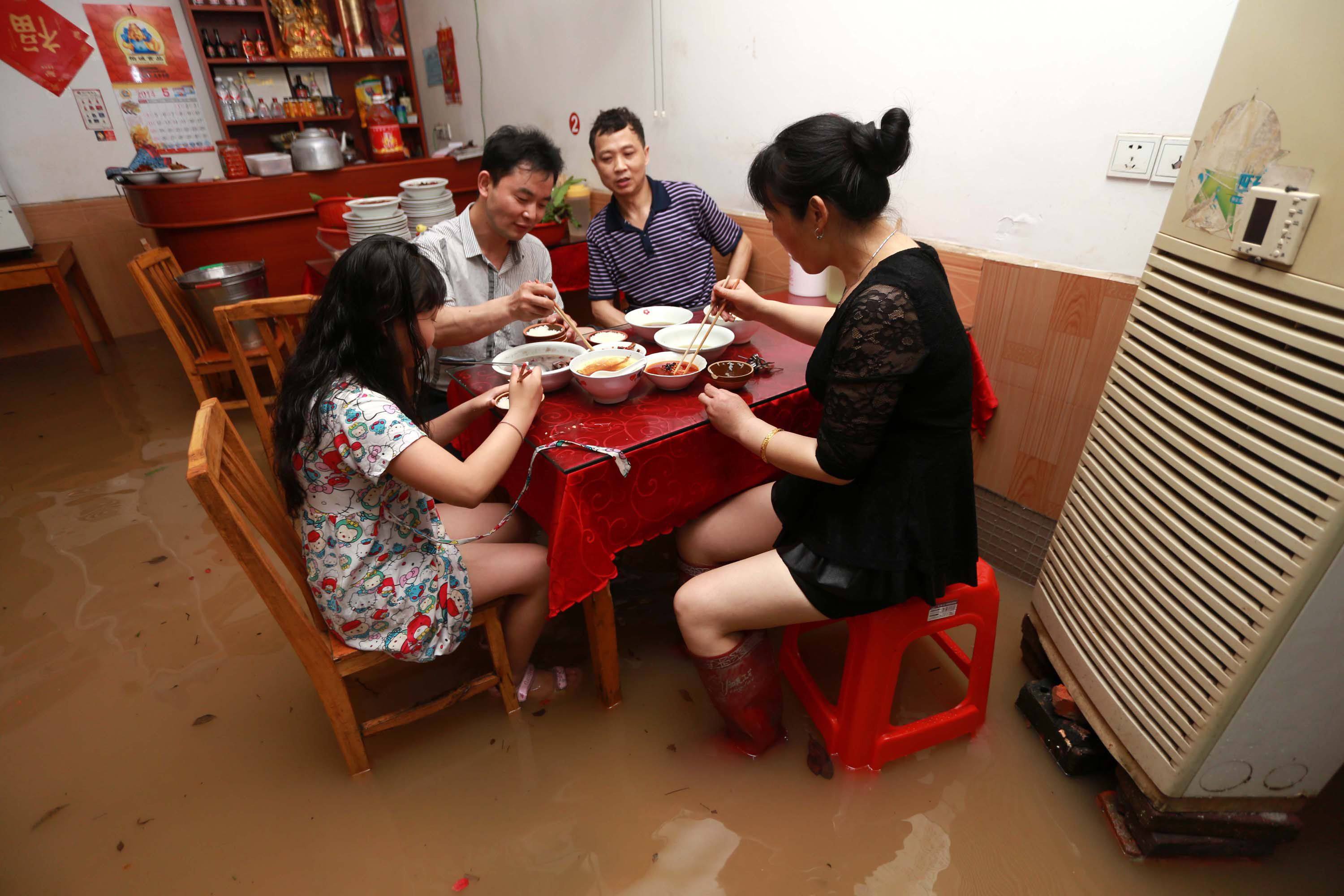 A family carries on eating during a flood in Liling, Hunan province. Photo: AFP
