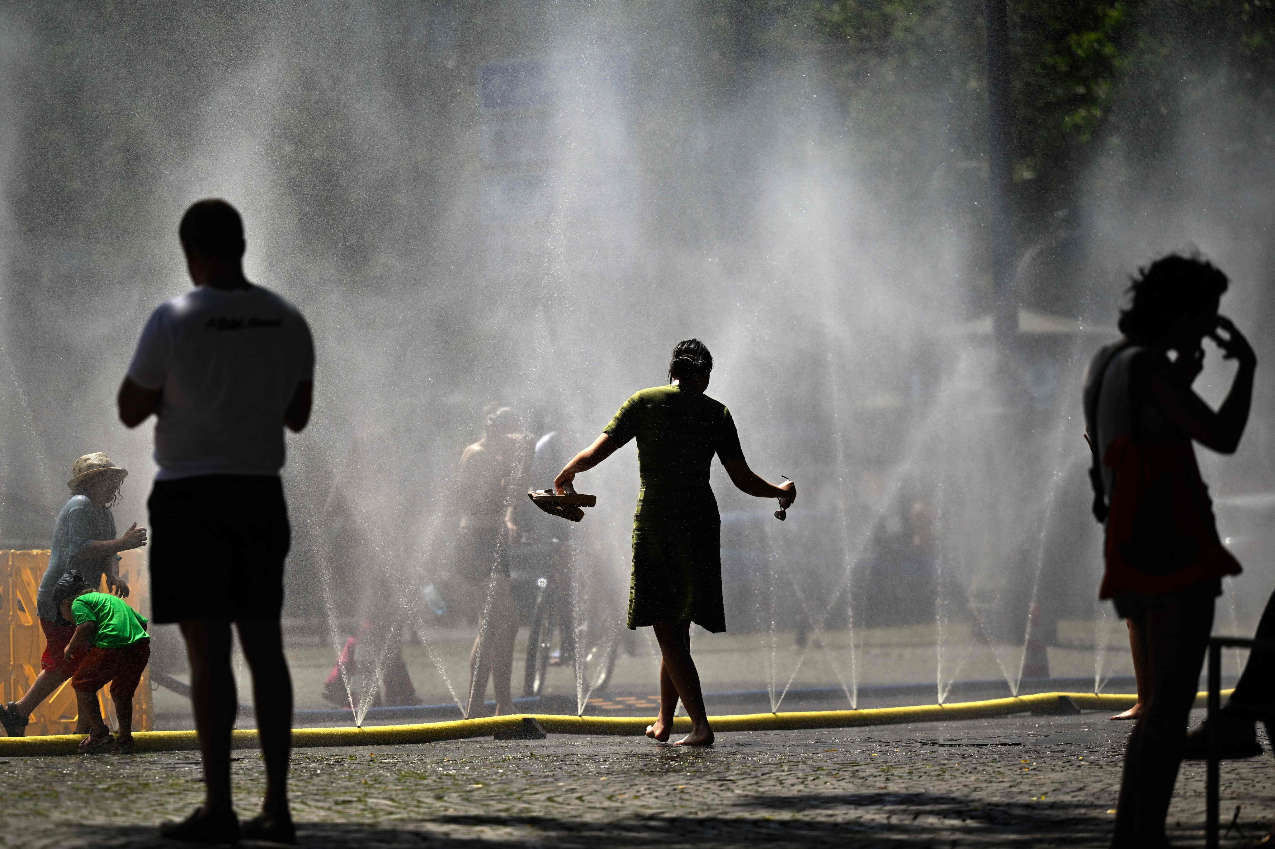 People cool down near water misters in Cologne, Germany, on Thursday. Photo: AFP
