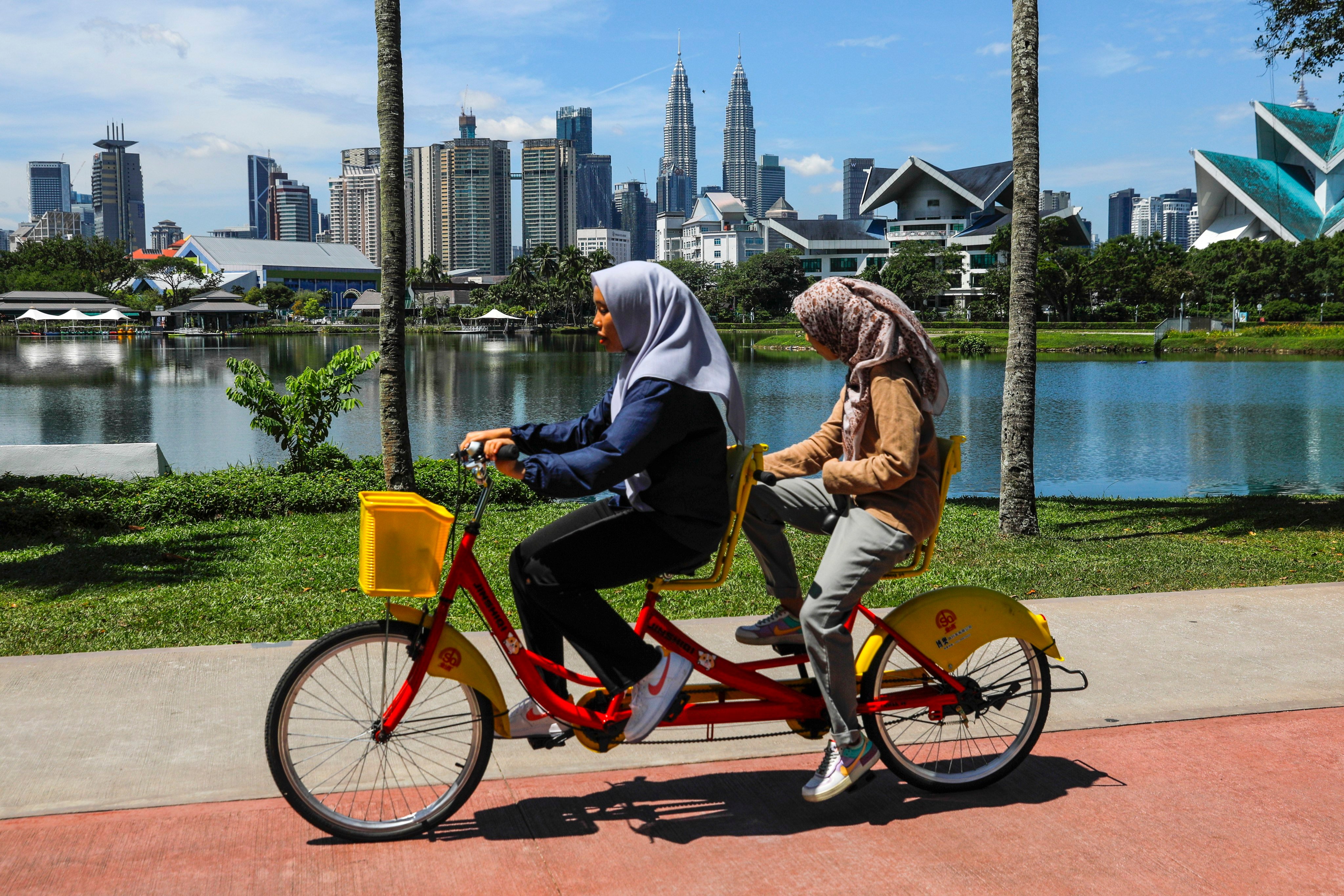 Women ride a tandem bicycle at a lake near the capital city in Kuala Lumpur, Malaysia. Photo: EPA-EFE