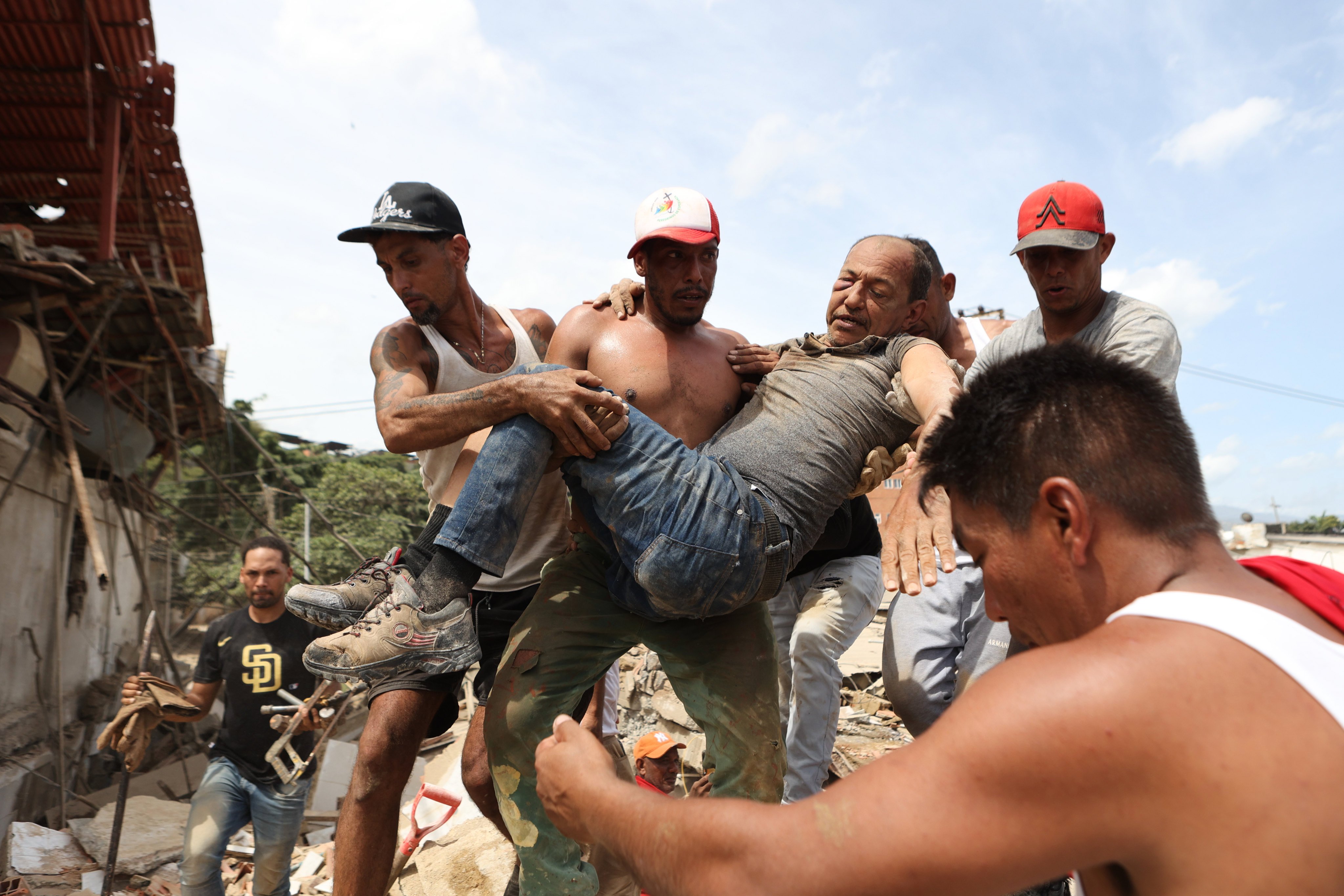 Neighbours carry a man rescued from the rubble in La Guaira. Photo: AP