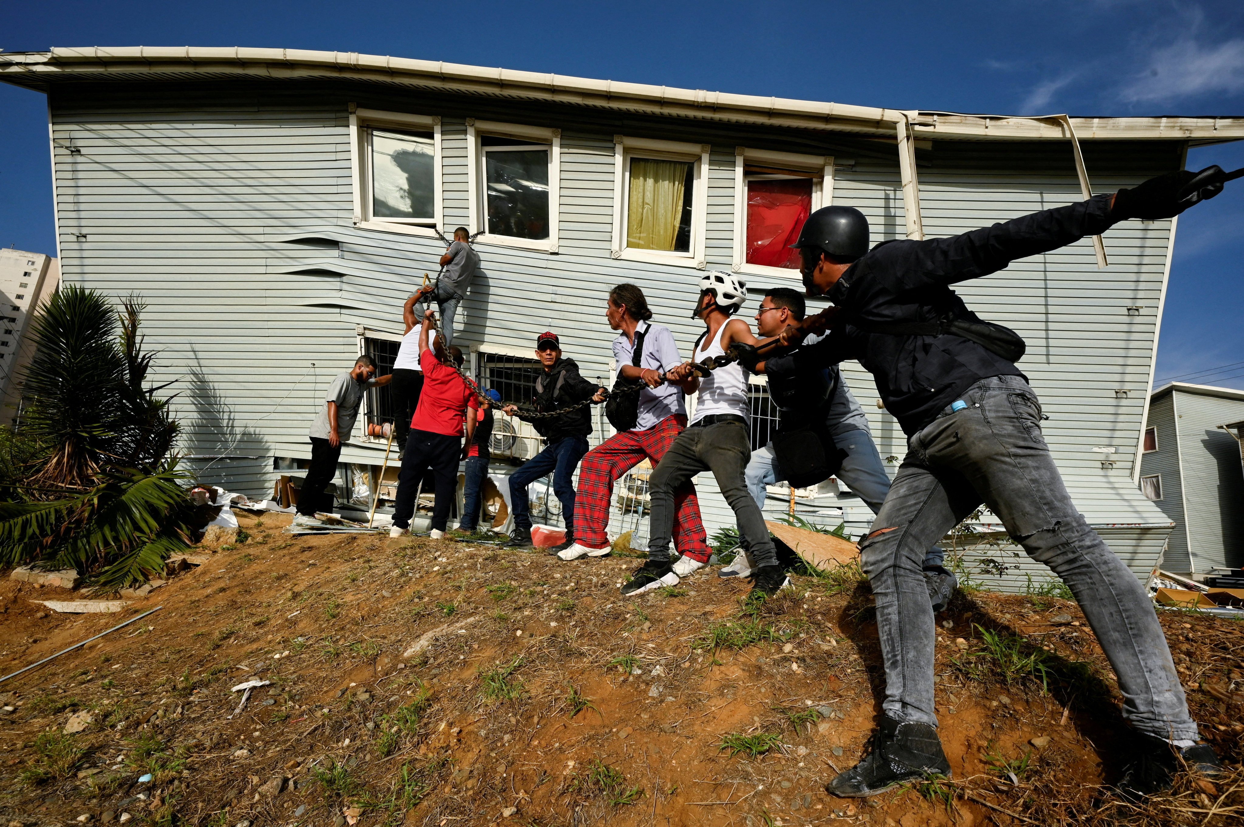 People assist in taking down a wall during rescue efforts. Photo: Reuters