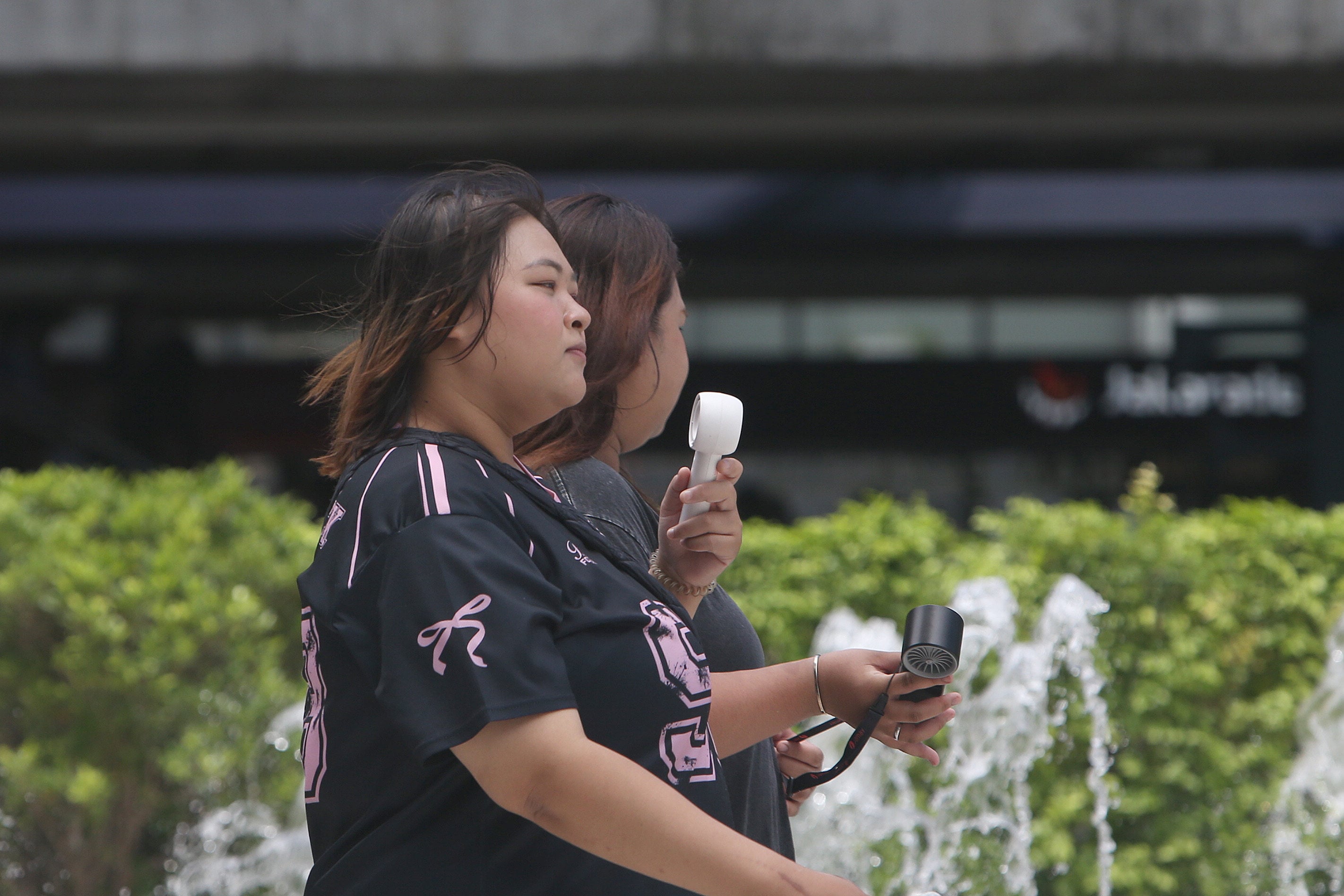 Pedestrians use portable fans while walking on a street in Bangkok, Thailand, on Tuesday. Photo: Xinhua