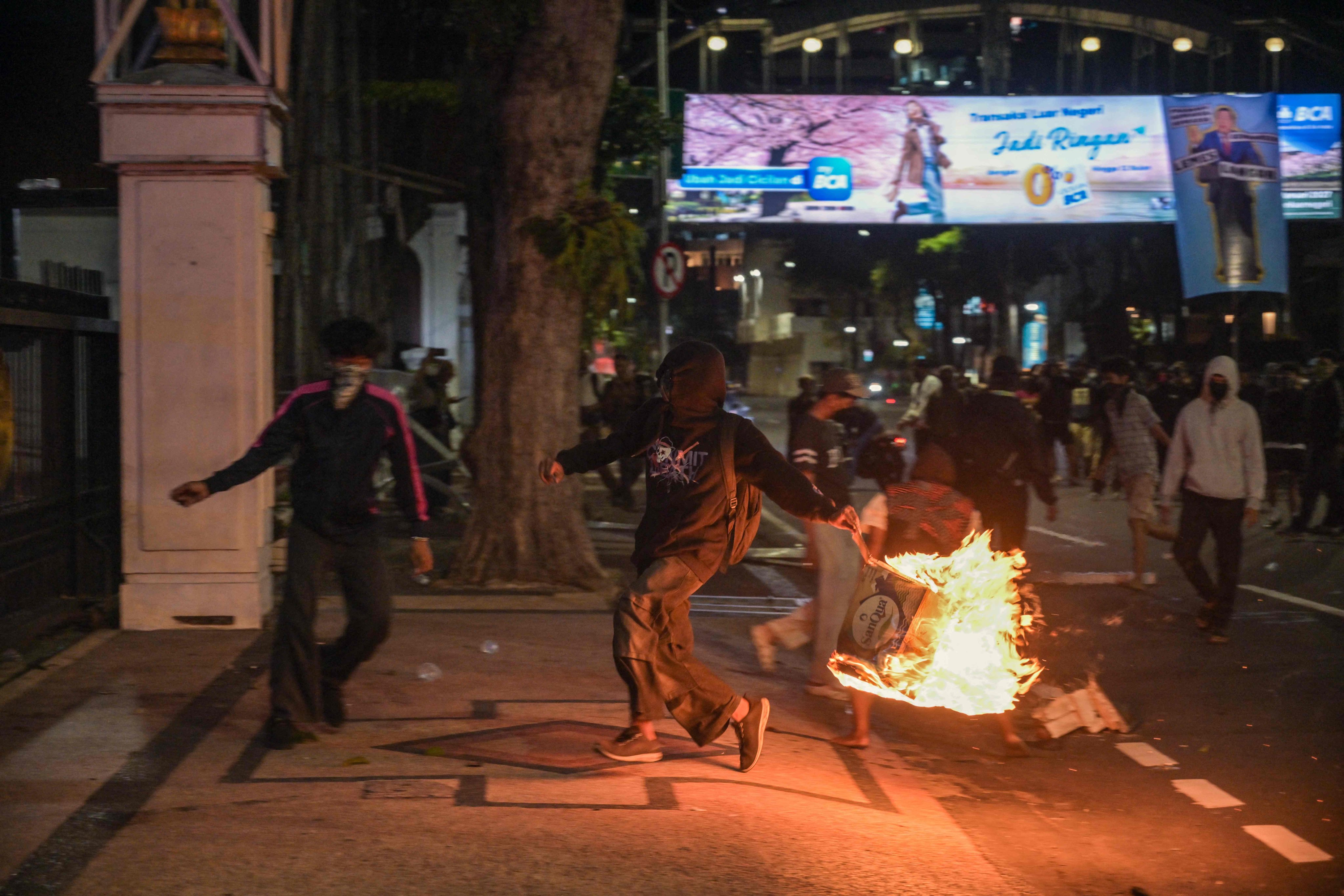 A student throws a box that has been set on fire at riot police during a protest in Surabaya on Friday. Photo: AFP
