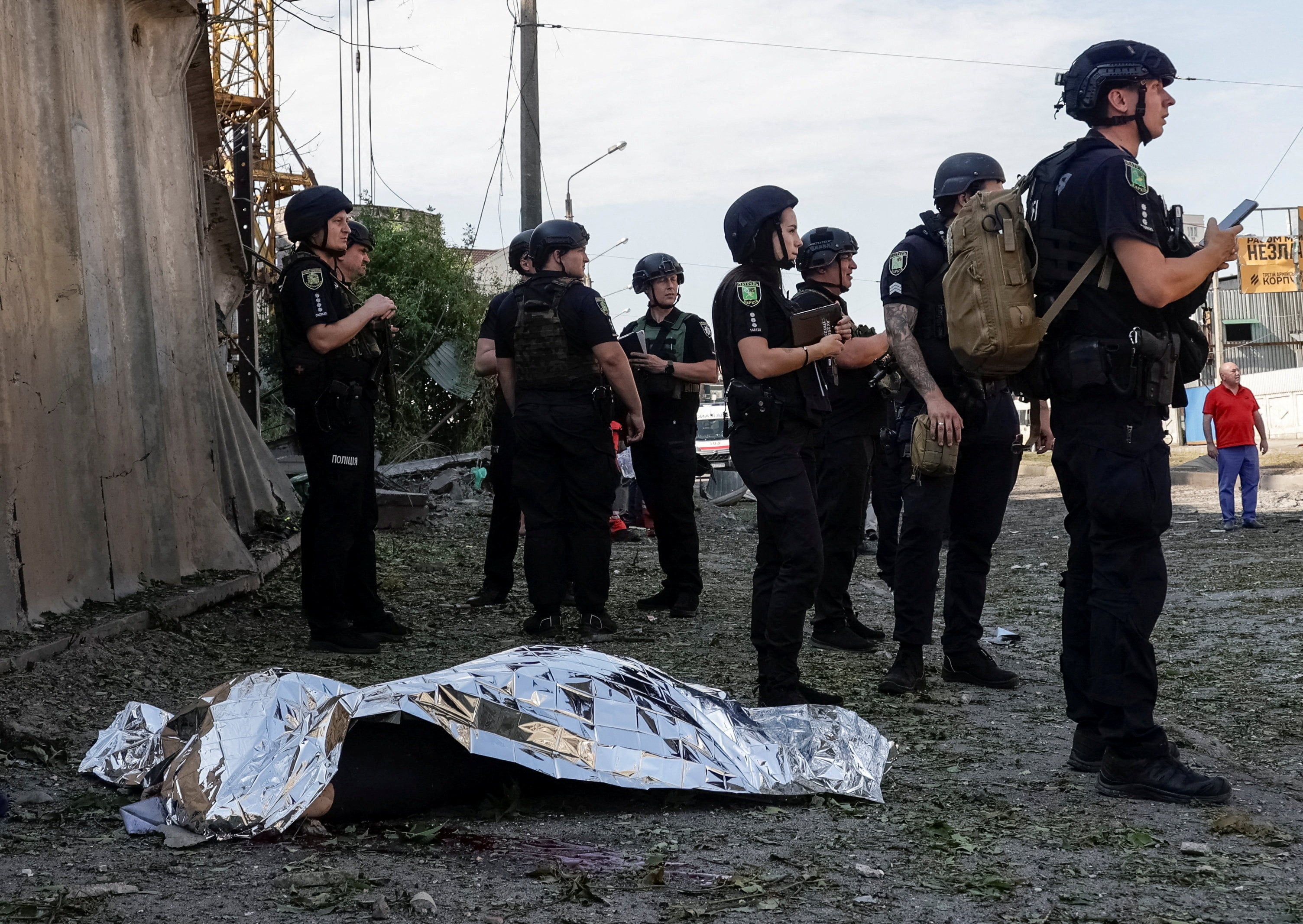 Police officers stand near the body of a resident killed during a Russian air strike in Kharkiv, Ukraine, on Monday. Photo: Reuters
