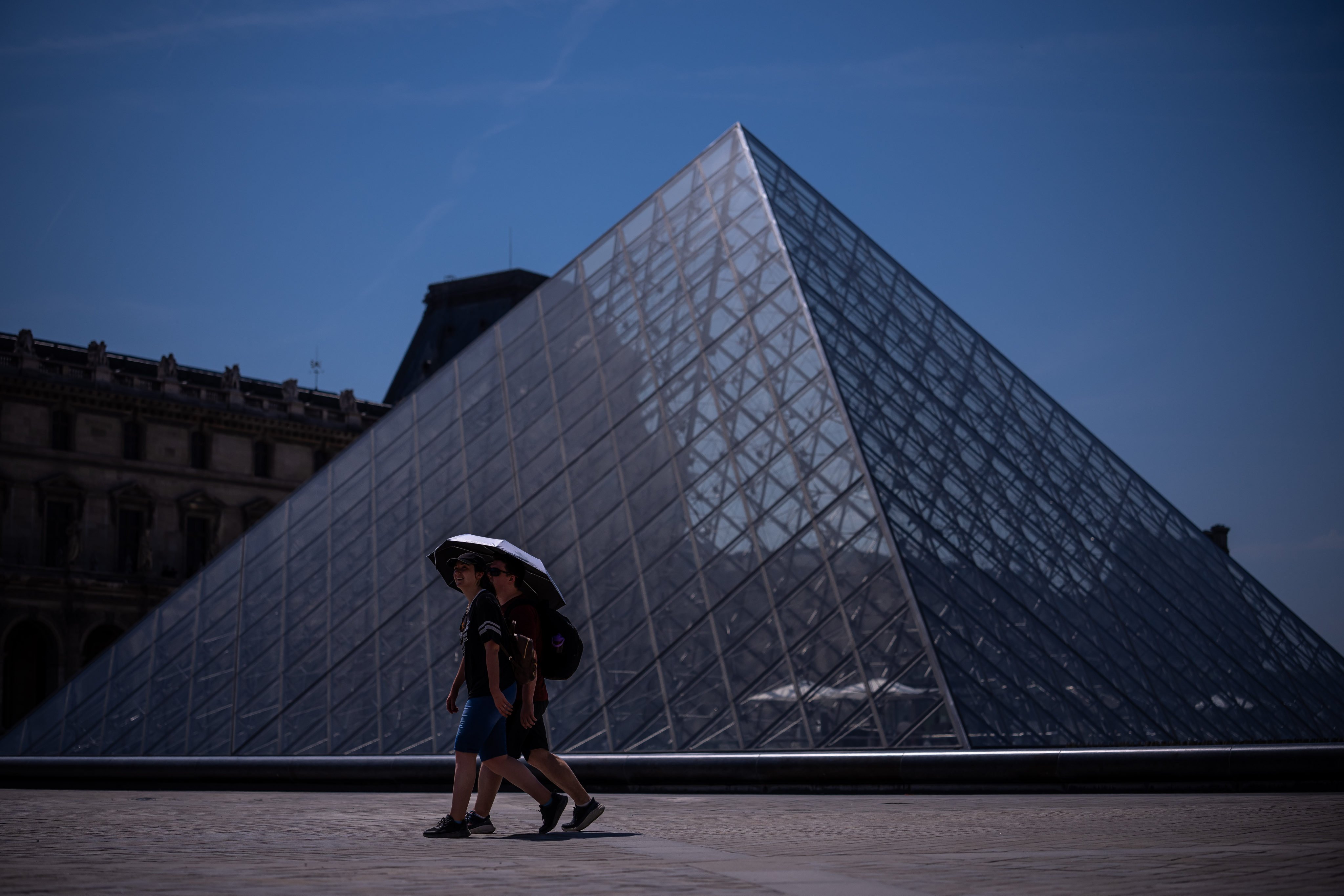 Tourists with an umbrella near the Louvre museum in Paris. Photo: AP