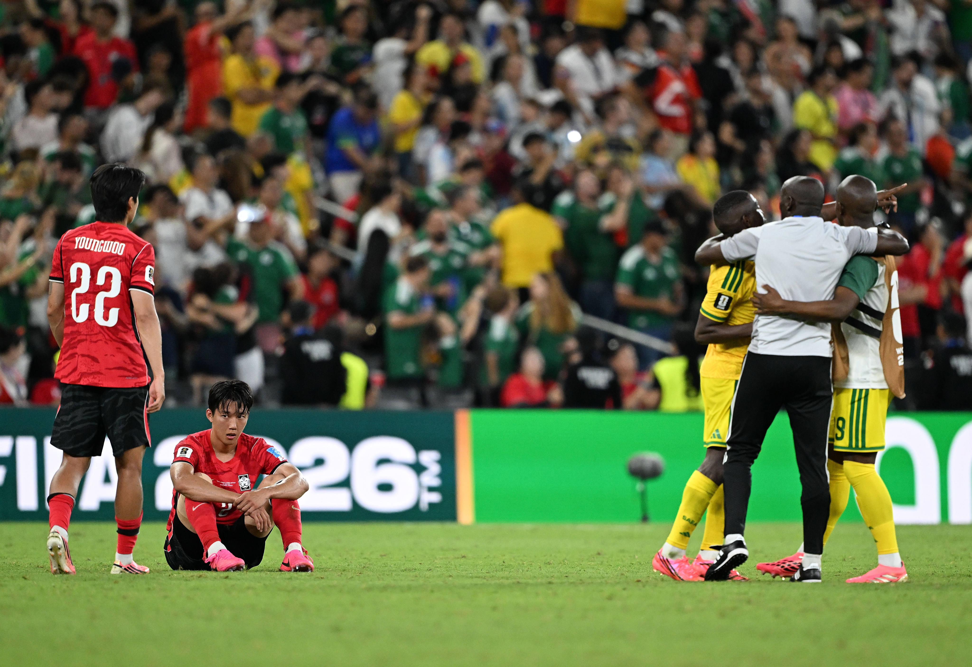 South Korean players look on as the South Africa team celebrate their 1-0 win, and qualification to the second round, last week. Photo: Xinhua