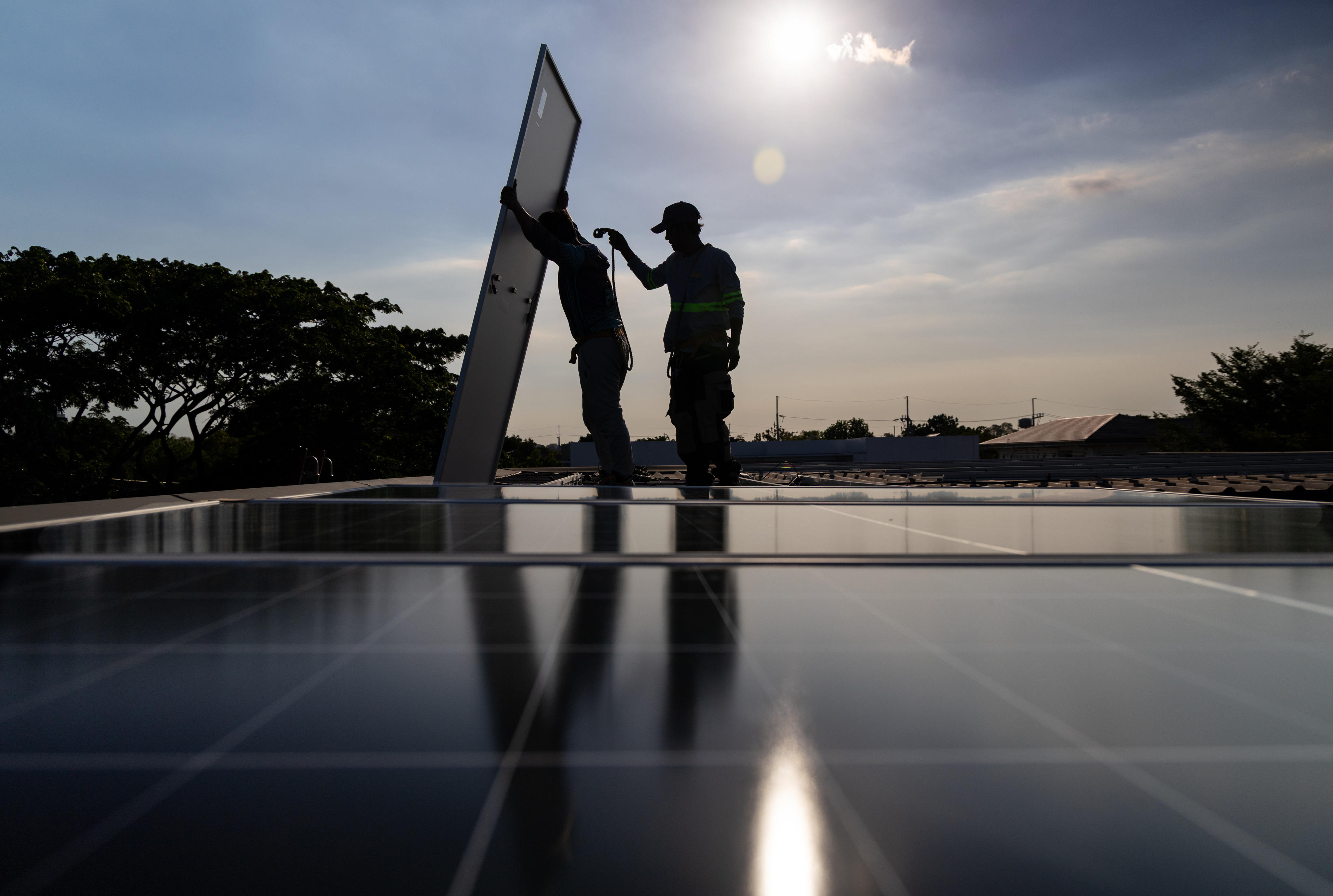 Workers install solar panels onto the roof of a home in Manila on April 30. Photo: AP