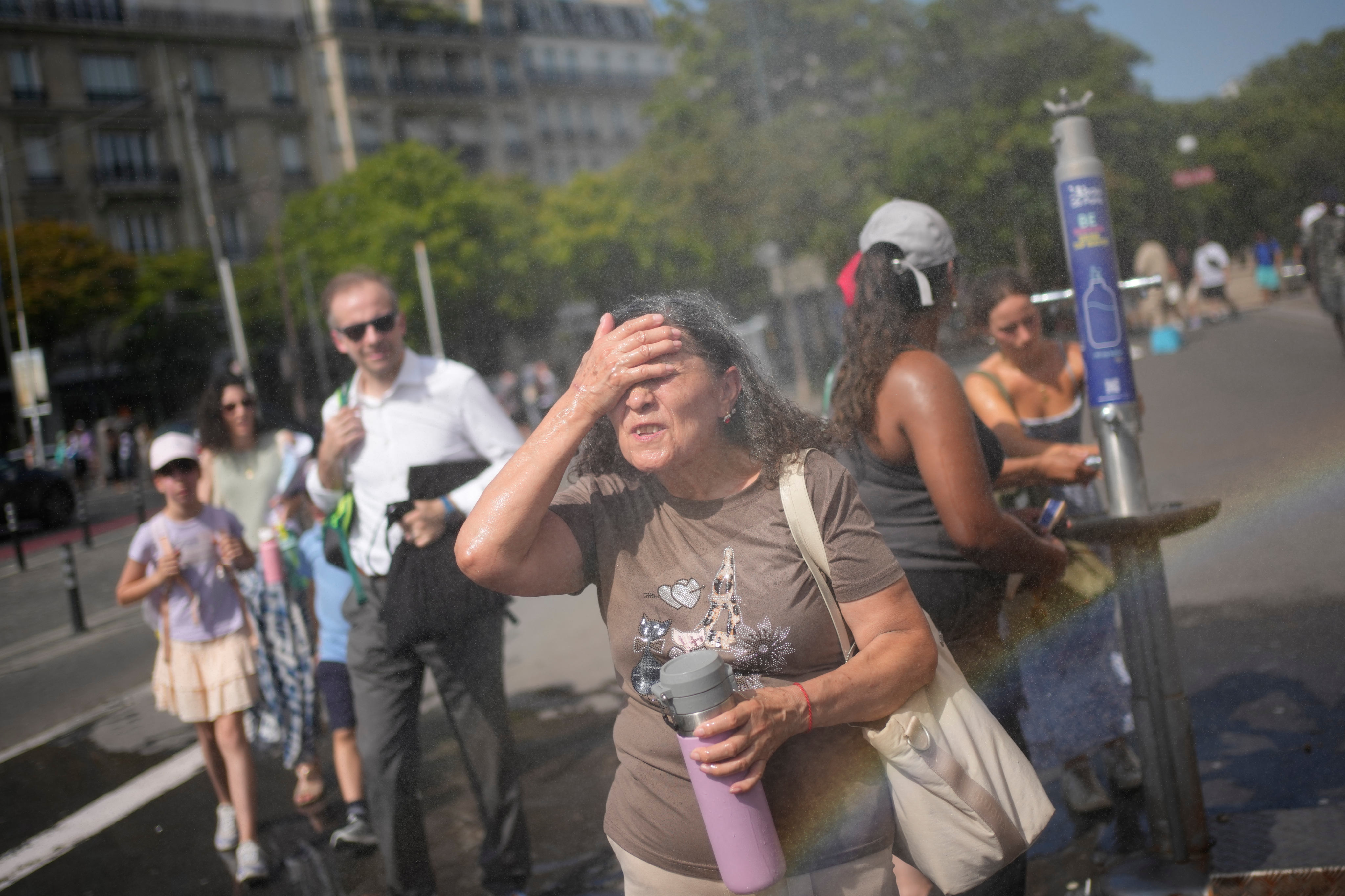 Tourists cool off at a public water fountain In Paris. Photo: AP