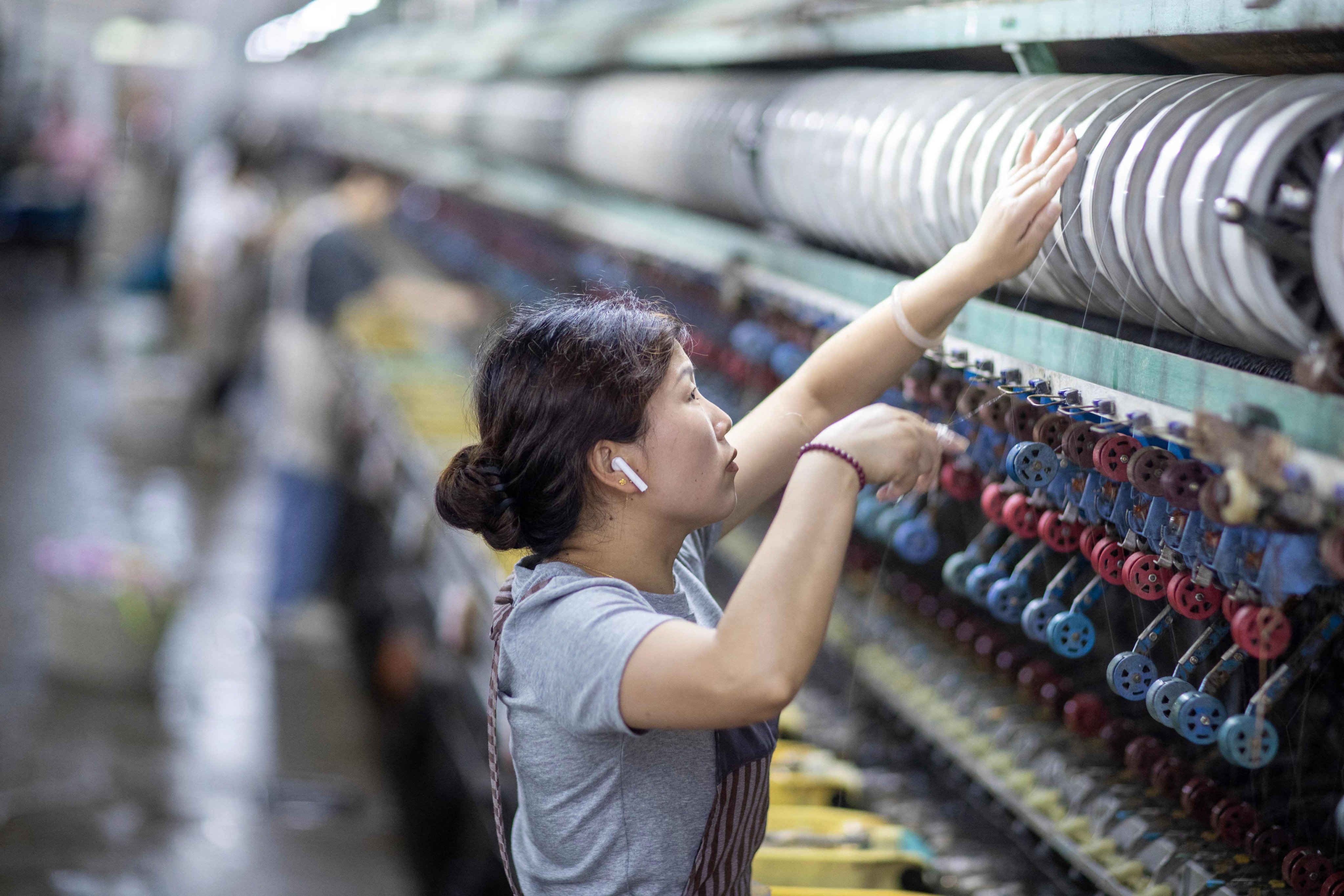A woman works on a production line at a silk processing workshop in Xinghua, in eastern China’s Jiangsu province, on June 23, 2026. Photo: AFP