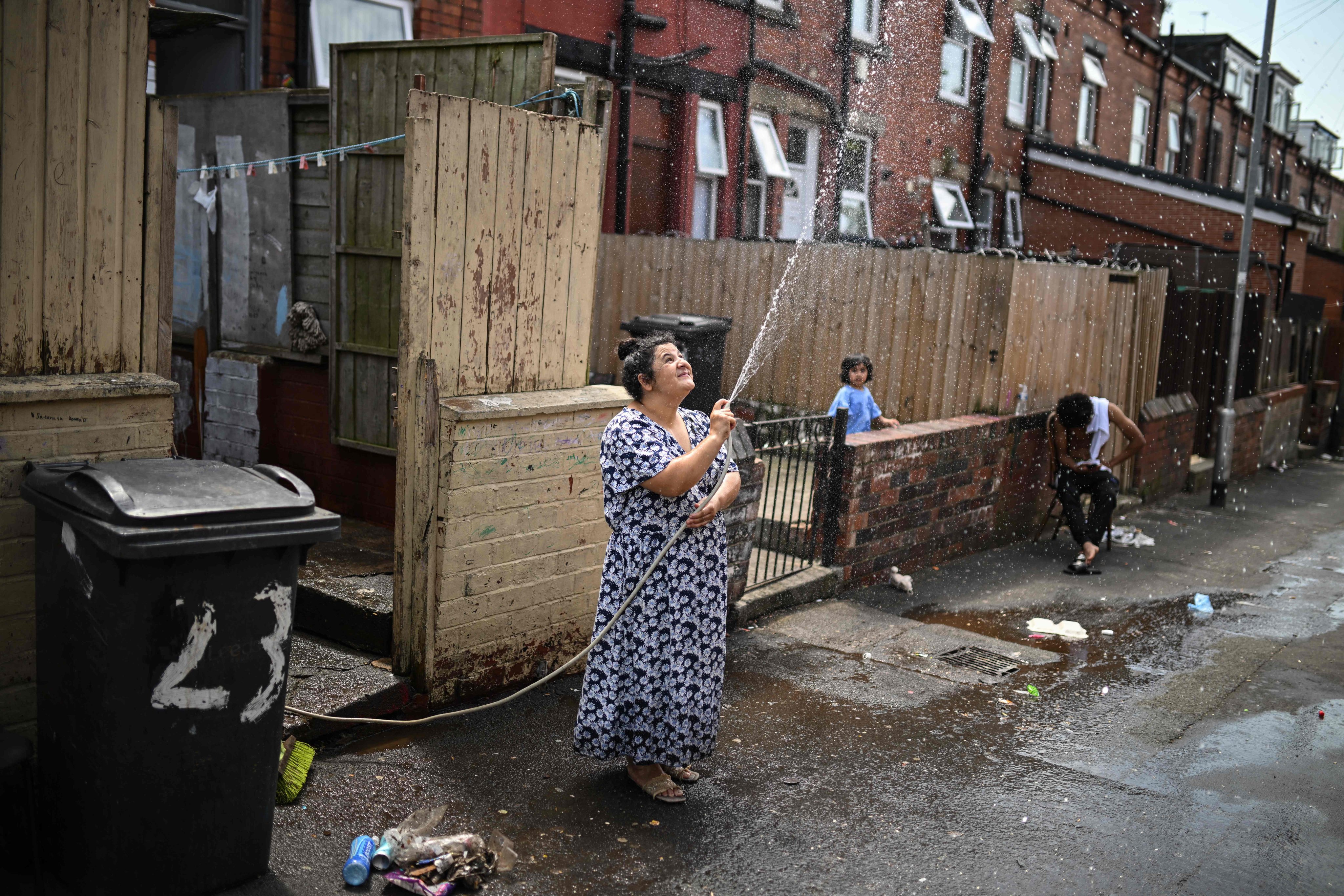 A woman sprays water to cool down the alley by her home in Leeds, northern England, on Thursday. Photo: AFP