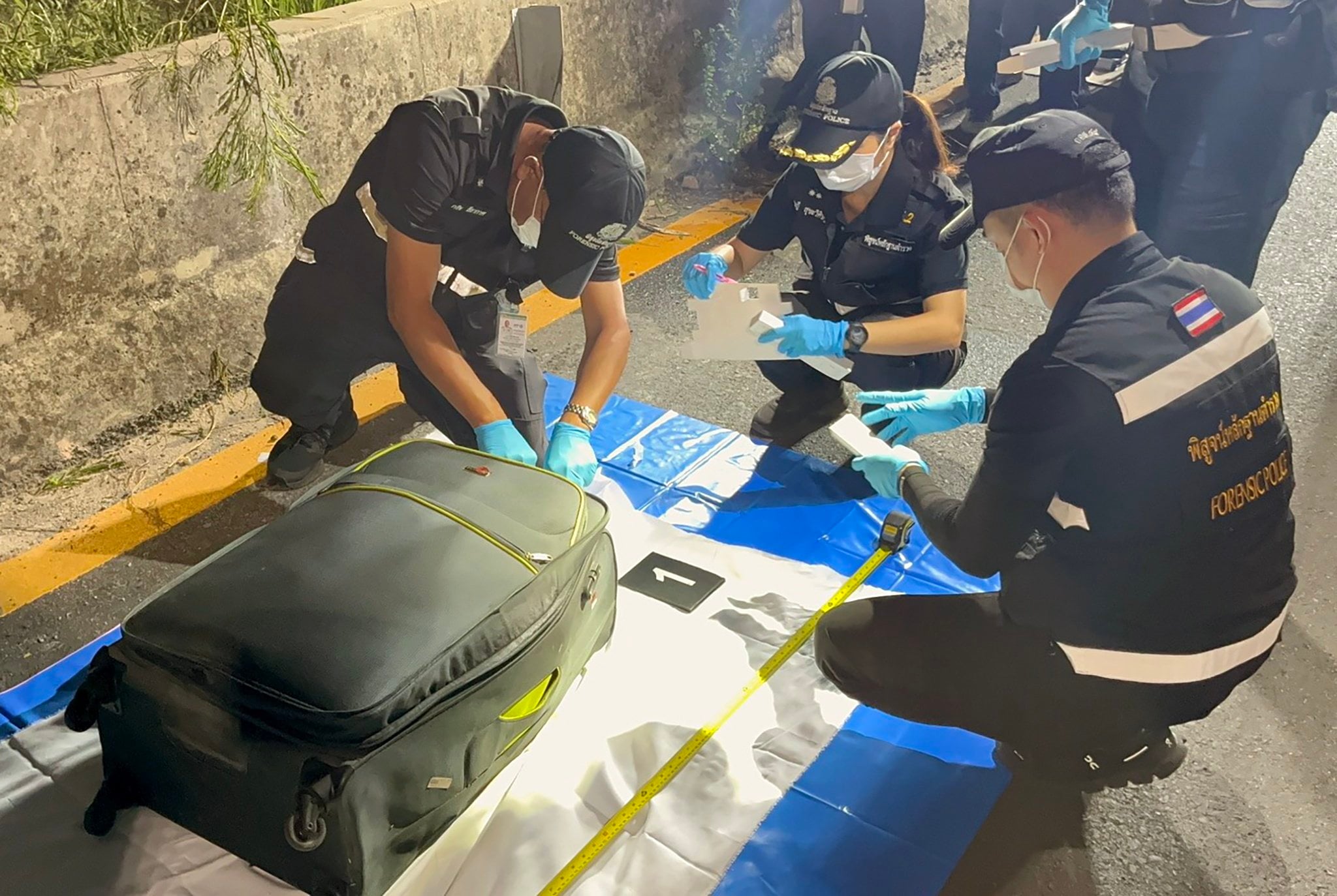 Thai forensic police officers on Friday inspect a suitcase containing the body of a Thai teenage girl believed to have been murdered by an Australian man near a railway track in Pattaya, Thailand. Photo: EPA