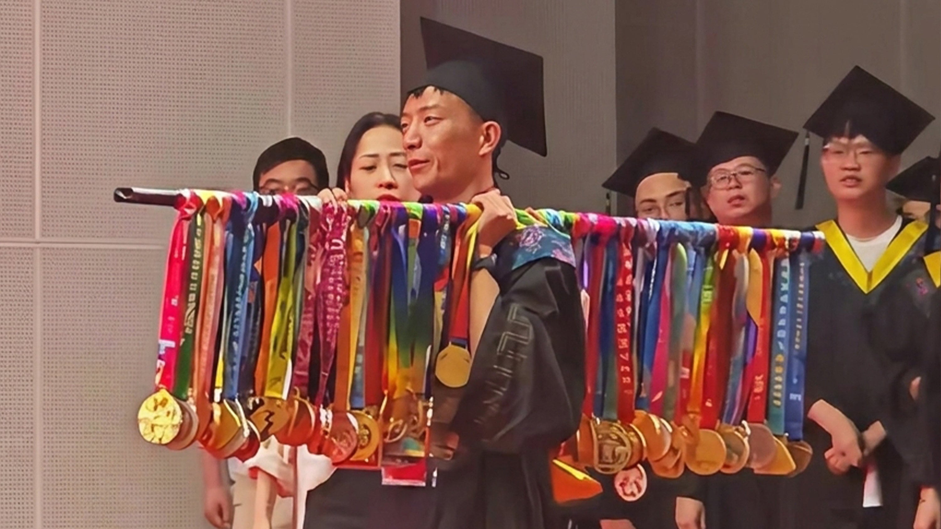 At his graduation, Jin Yanwei showcased over 70 marathon medals he earned in two years using a shoulder pole. Photo: Baidu