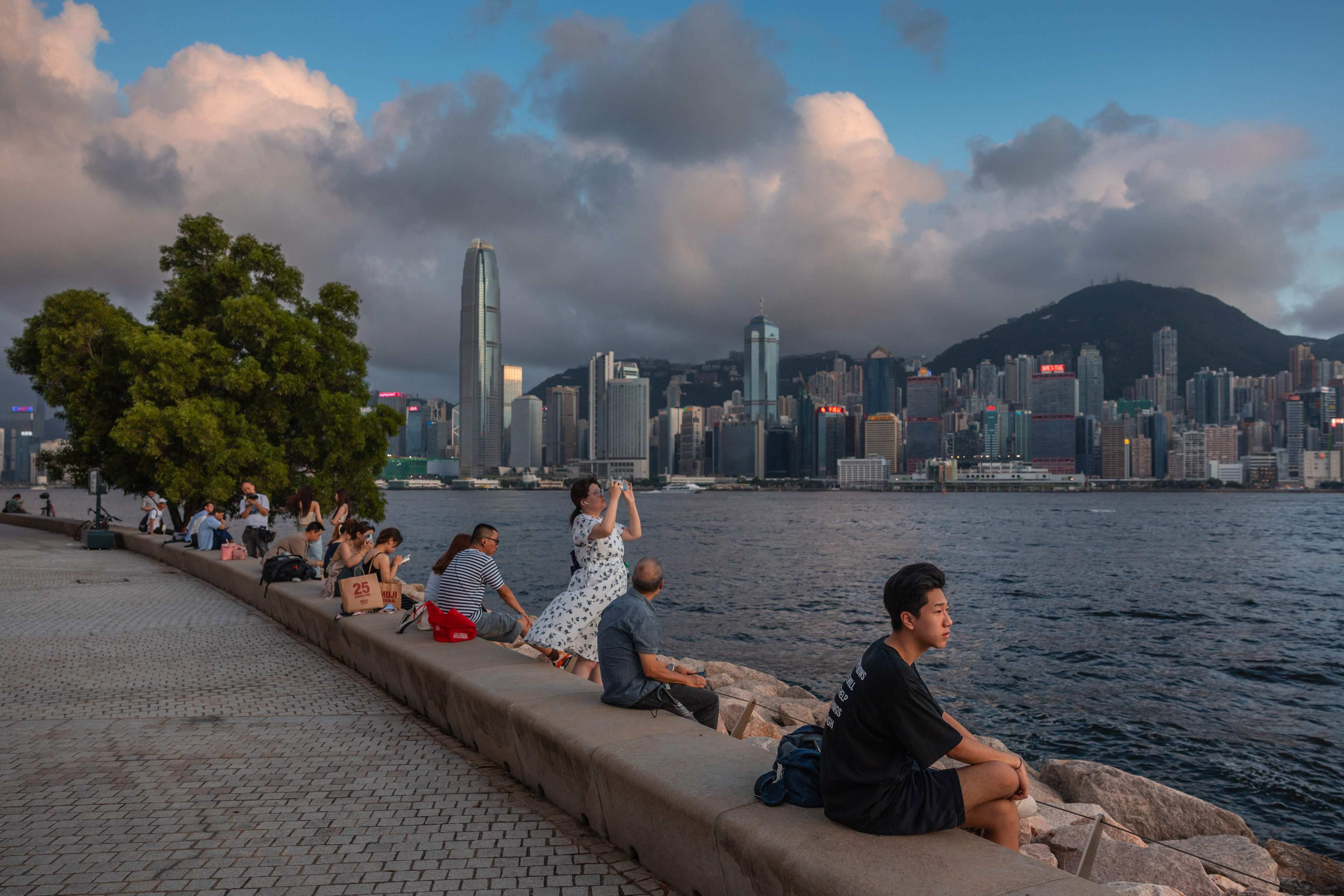People sit on a promenade along Victoria Harbour in Hong Kong on June 23. Photo: AFP