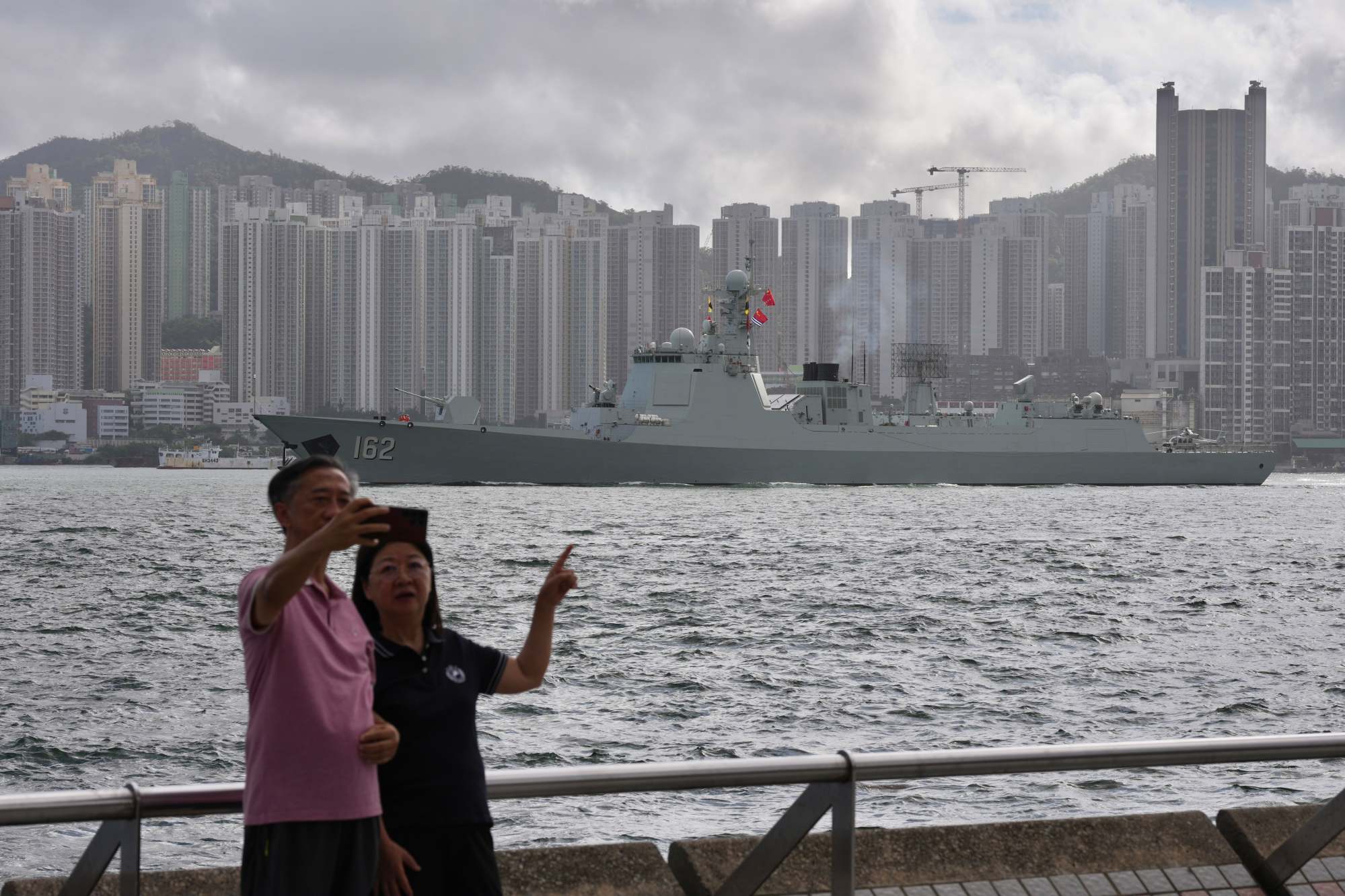 A couple take a selfie at the Sai Wan Ho promenade, with the guided-missile destroyer Nanning in the background. Photo: Karma Lo
