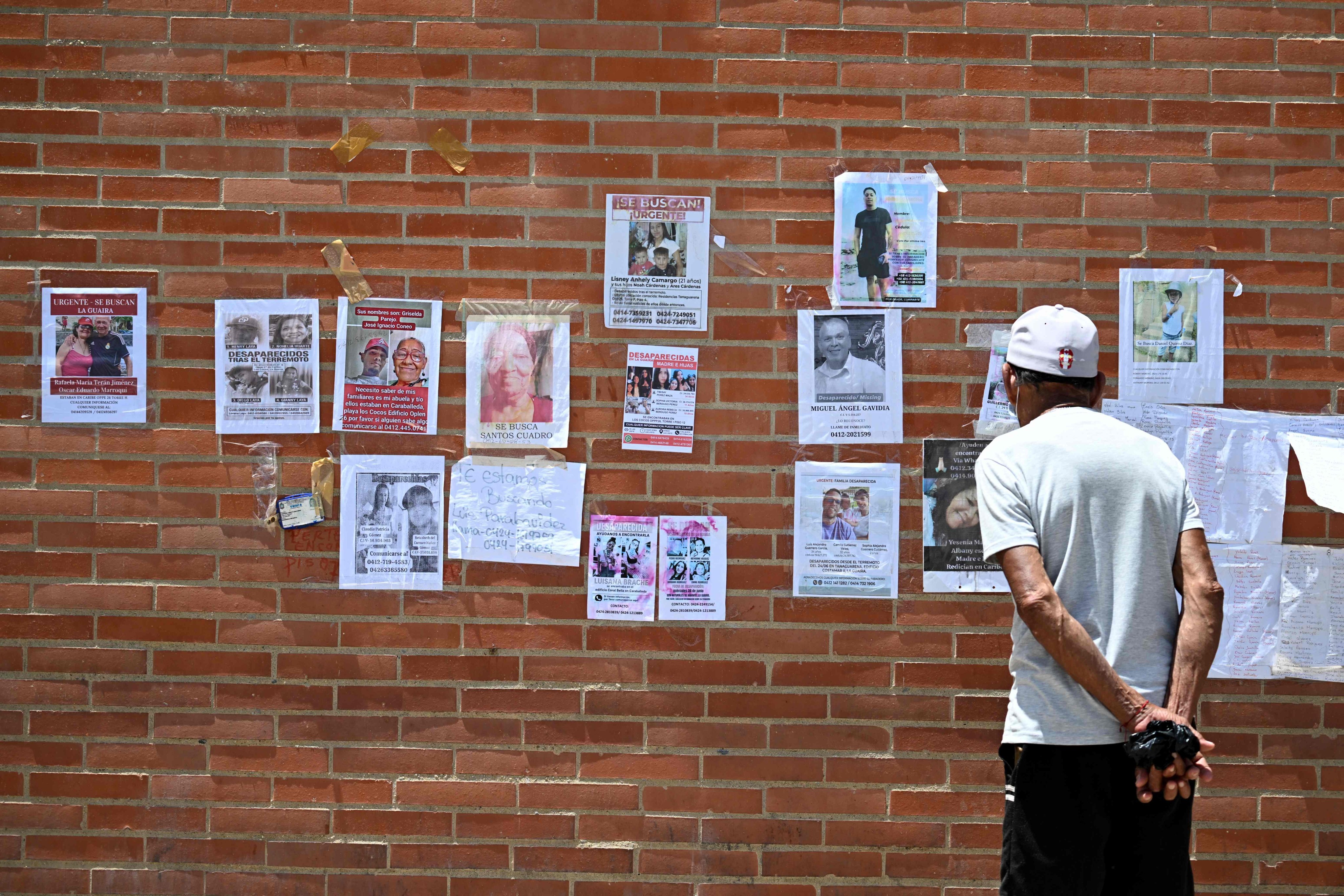 A man looks at pictures of missing people. Photo: AFP