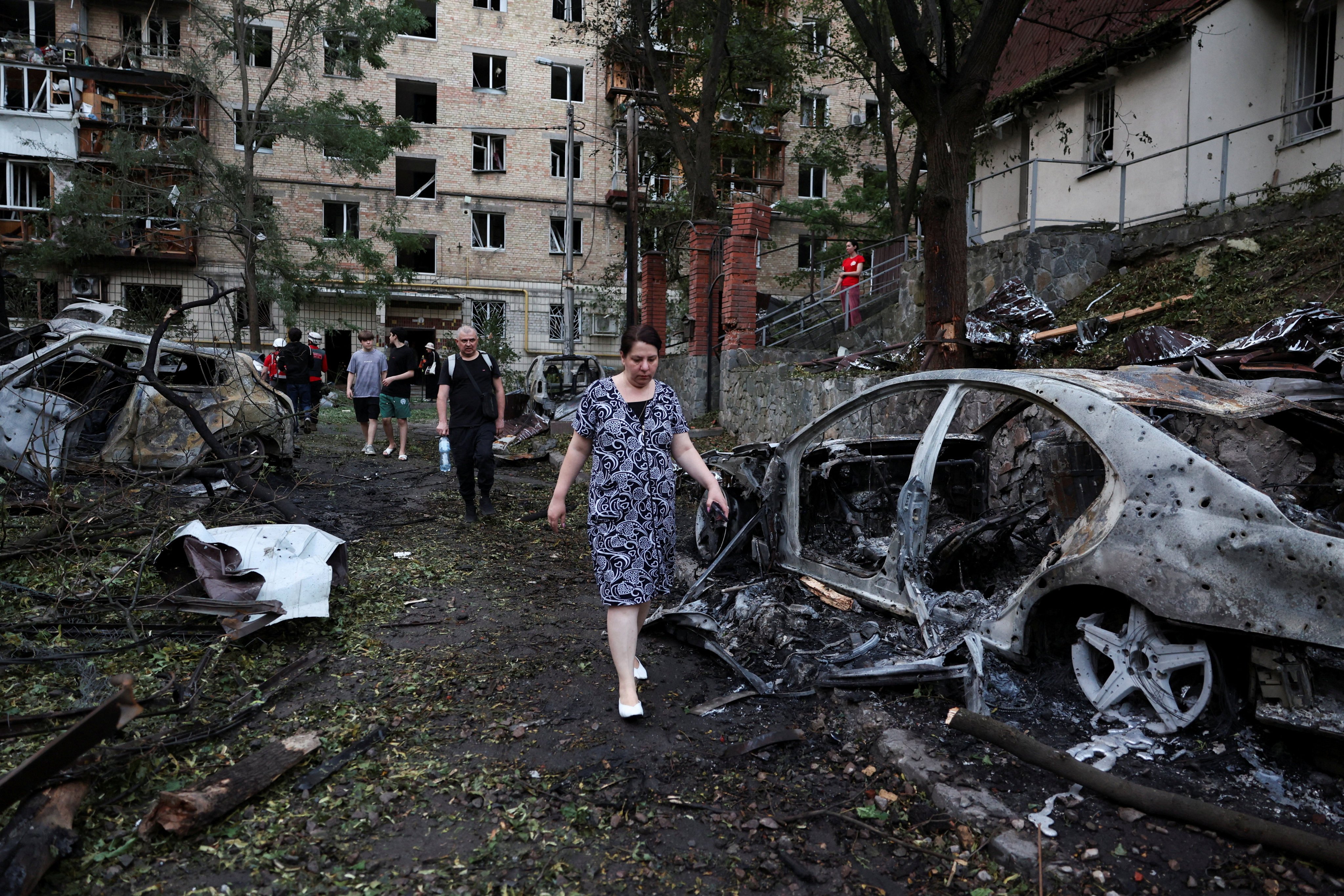 Residents walk past burned out cars. Photo: Reuters