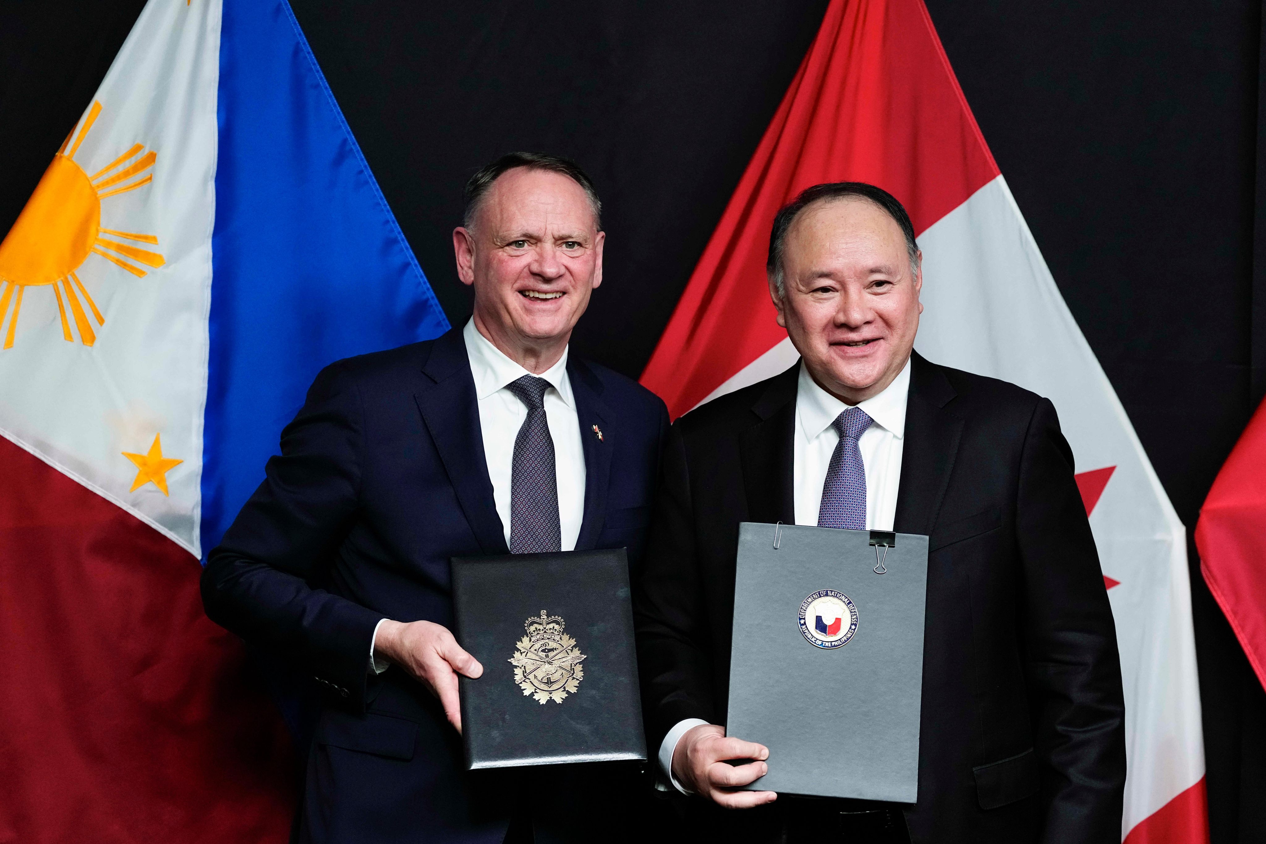 Canadian Minister of National Defence David McGuinty (left) and Philippine Secretary of National Defence Gilberto Teodoro take part in a signing ceremony in Ottawa on June 11. Photo: AP