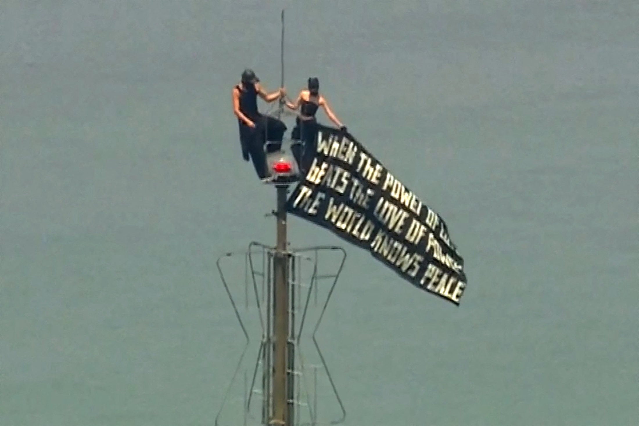 Two people display a banner atop the Empire State Building on Wednesday. Photo: ABC Affiliate WABC via Reuters