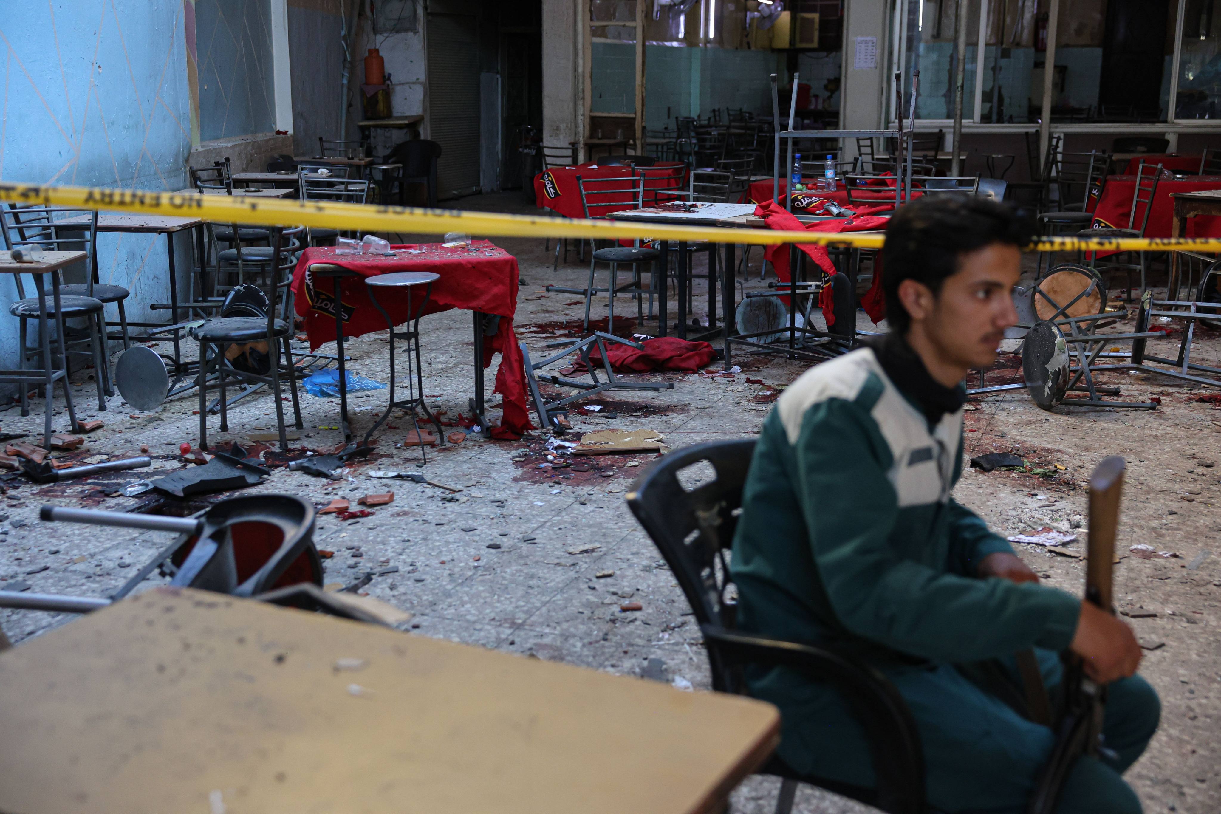 A member of the Syrian security forces keeps watch inside a Damascus cafe following a deadly bomb blast. Photo: dpa