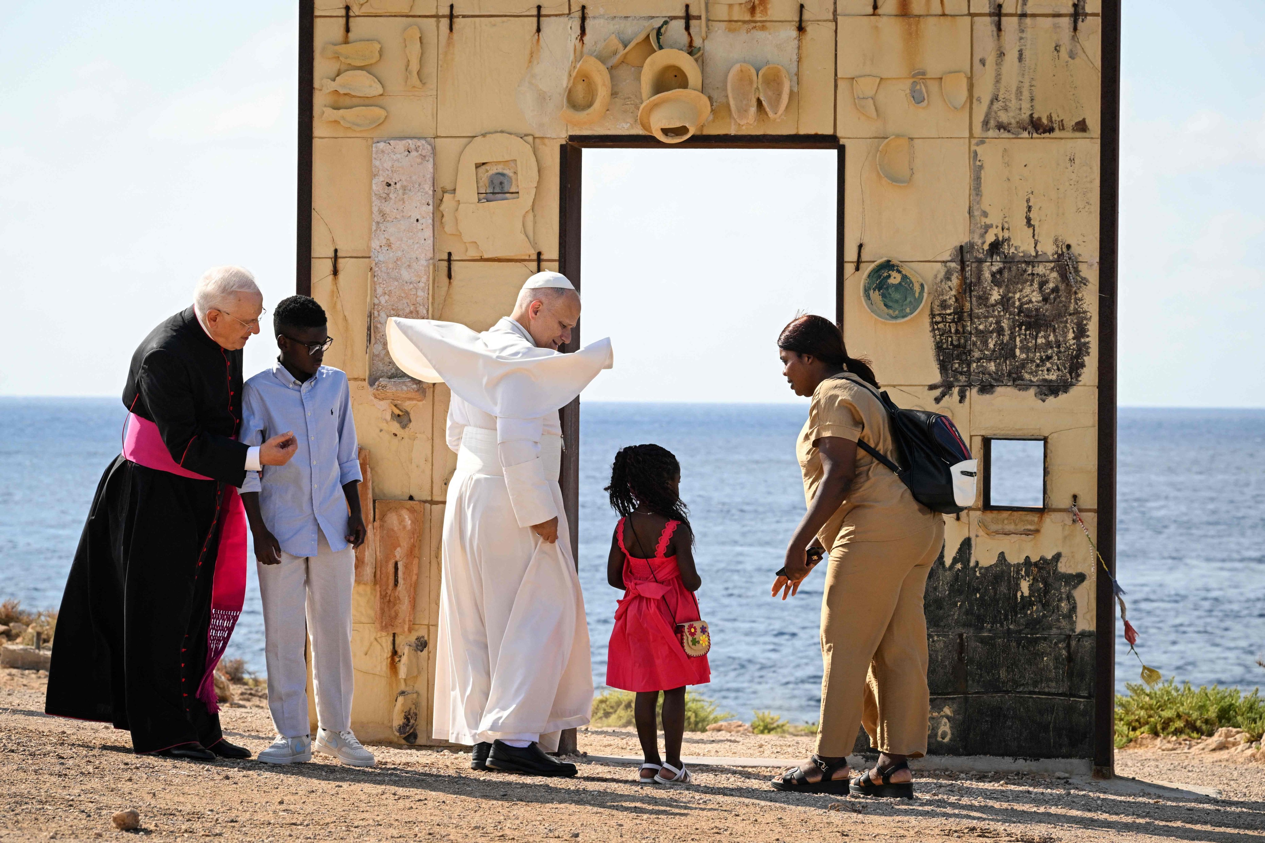 Pope Leo XIV (centre) meets with a migrant family by the arch of the monument Door of Europe, during a visit to Lampedusa island, Italy, on Saturday. Photo: AFP
