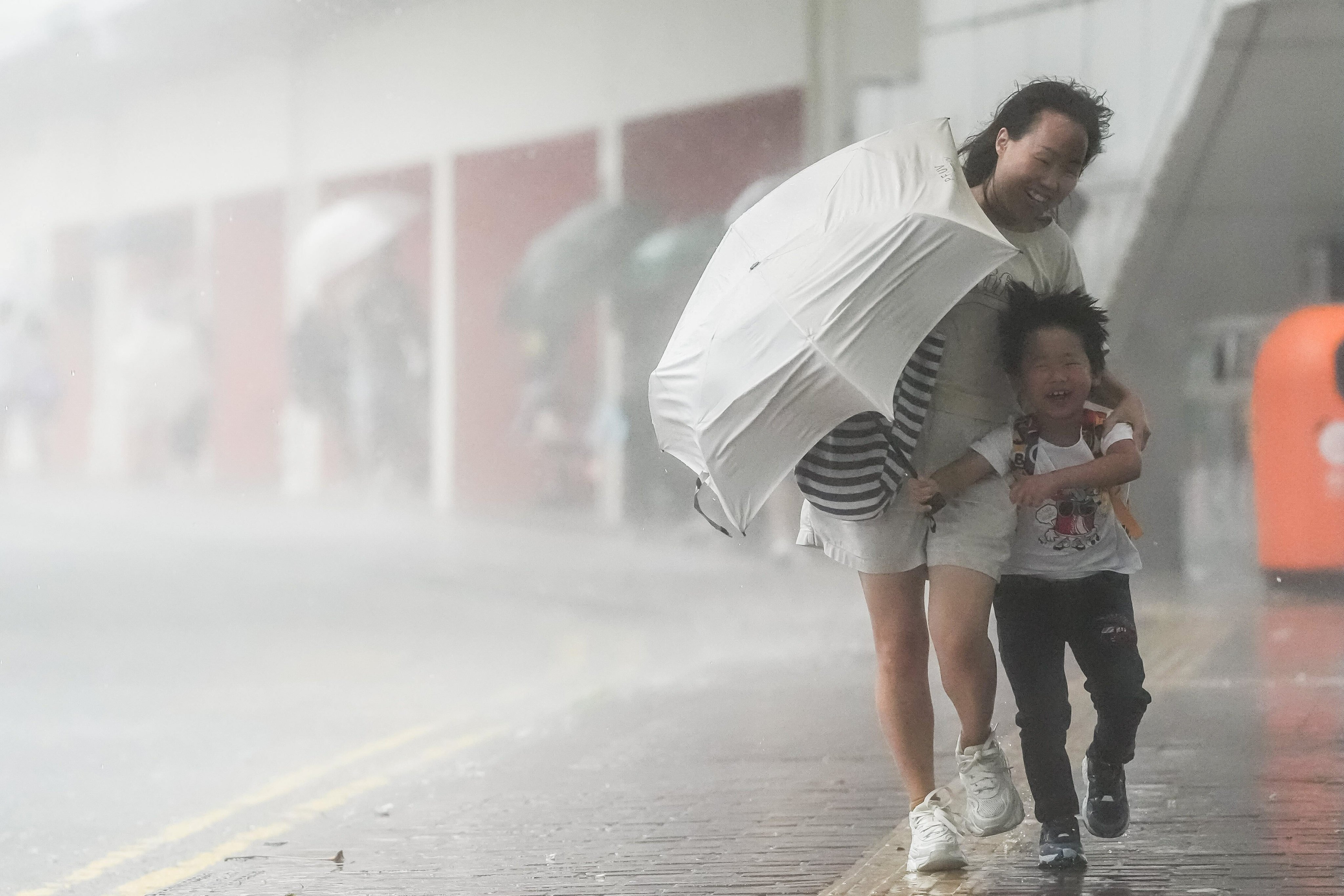 A woman and child try to shield themselves from heavy rain in Mei Foo. Photo: Elson Li