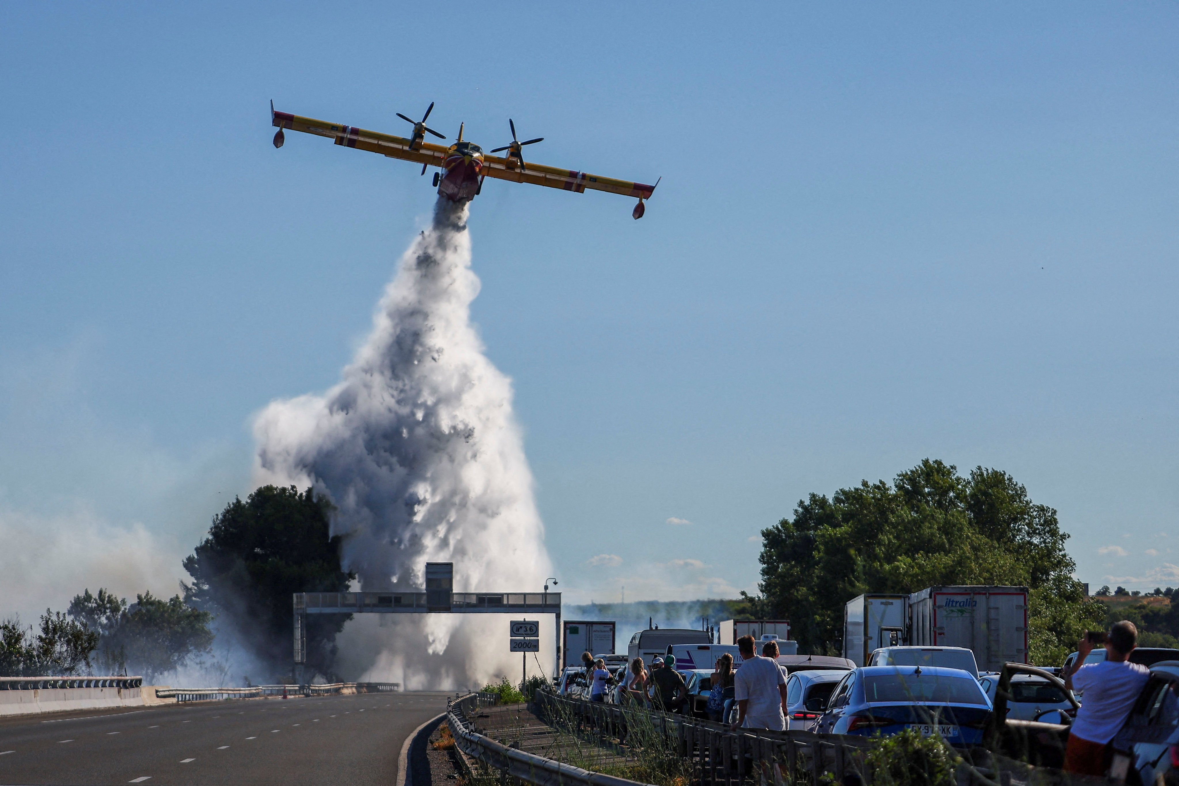 People watch as a firefighting plane tries to battle a wildfire by a motorway near Beziers, France, on Friday. Photo: Reuters