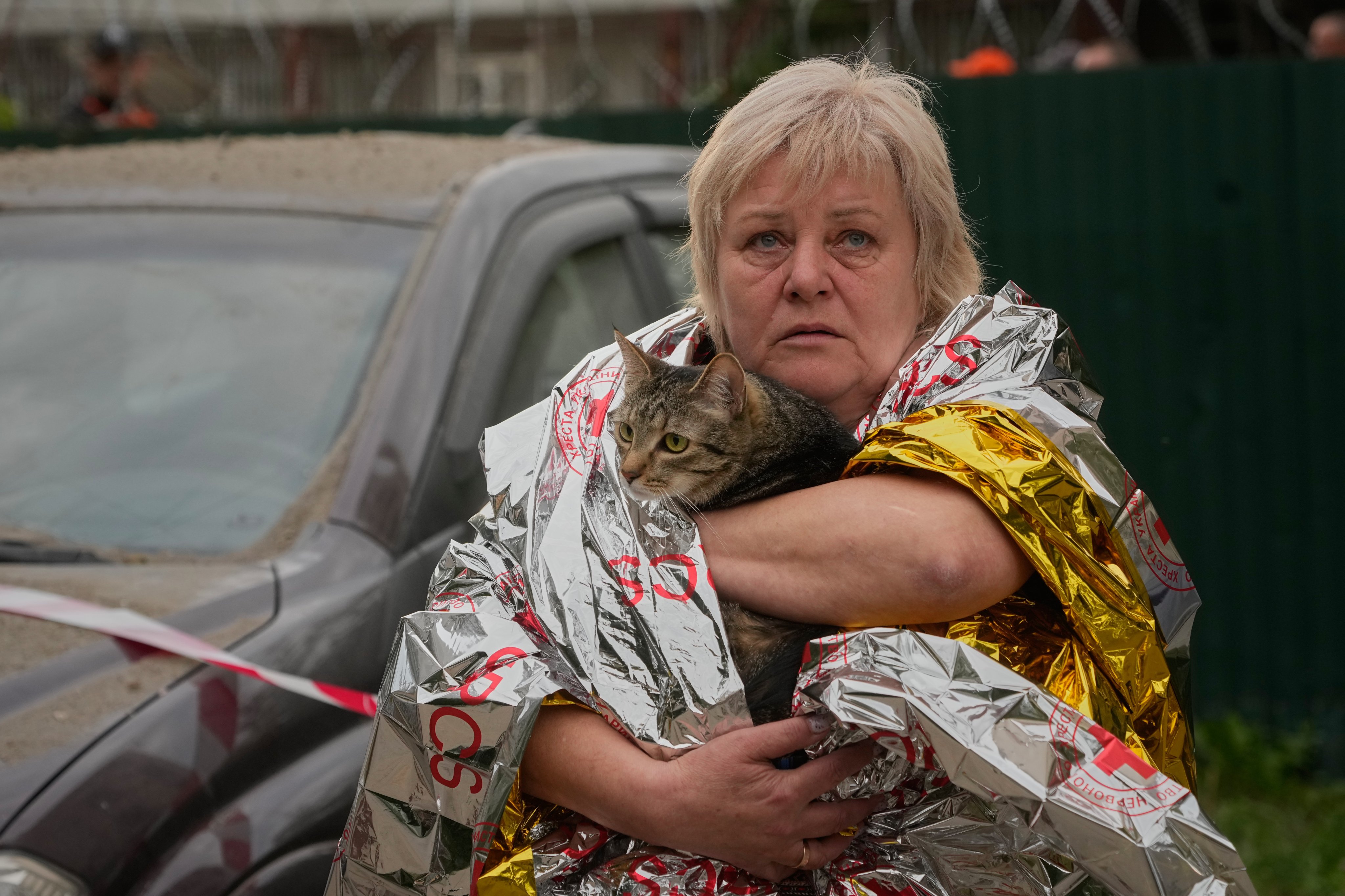A woman carries her cat out of a damaged building. Photo: AP