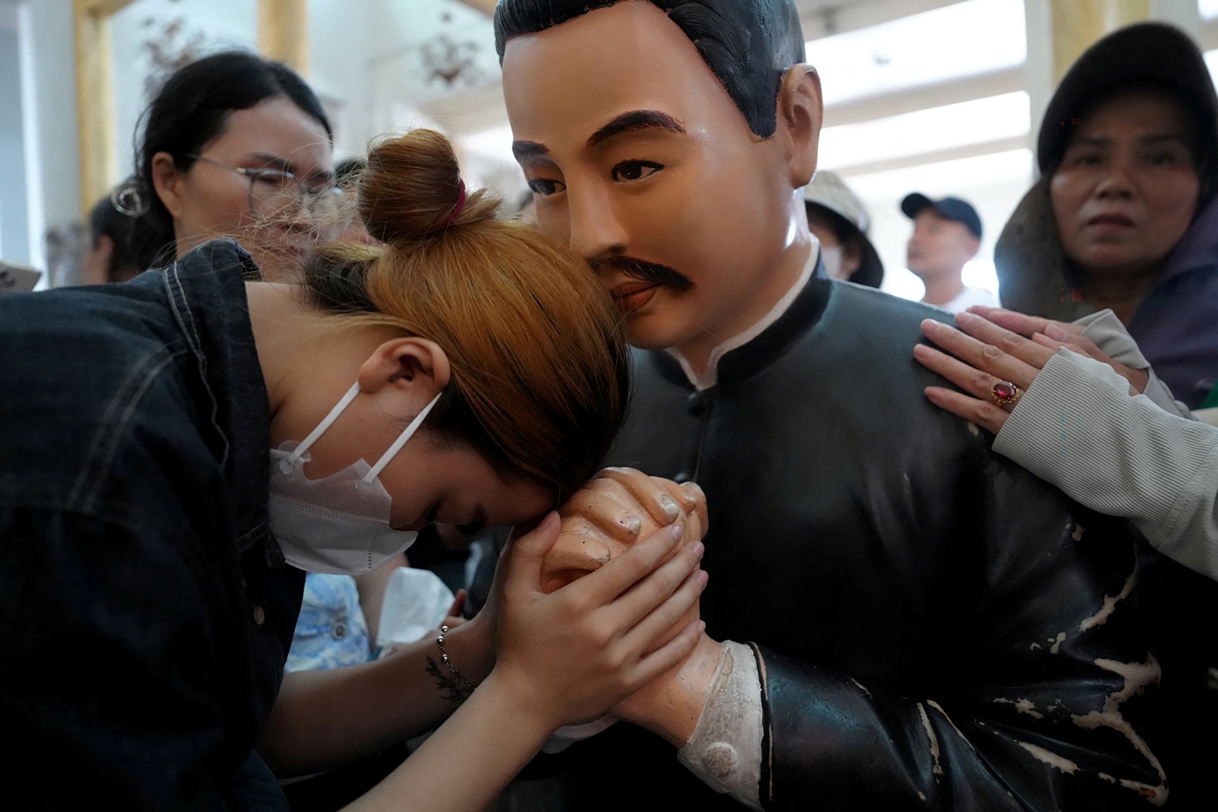 A woman holds the hand of a statue of the late priest Francis Xavier Truong Buu Diep at his beatification mass at the Tac Say Pilgrimage Center in Ca Mau province in southern Vietnam on July 2, 2026. Tens of thousands of Catholics flocked to a small parish in the Mekong Delta on July 2 for the first beatification ceremony held on Vietnamese soil, with an envoy of Pope Leo XIV presiding over the special mass. (Photo by AFP)