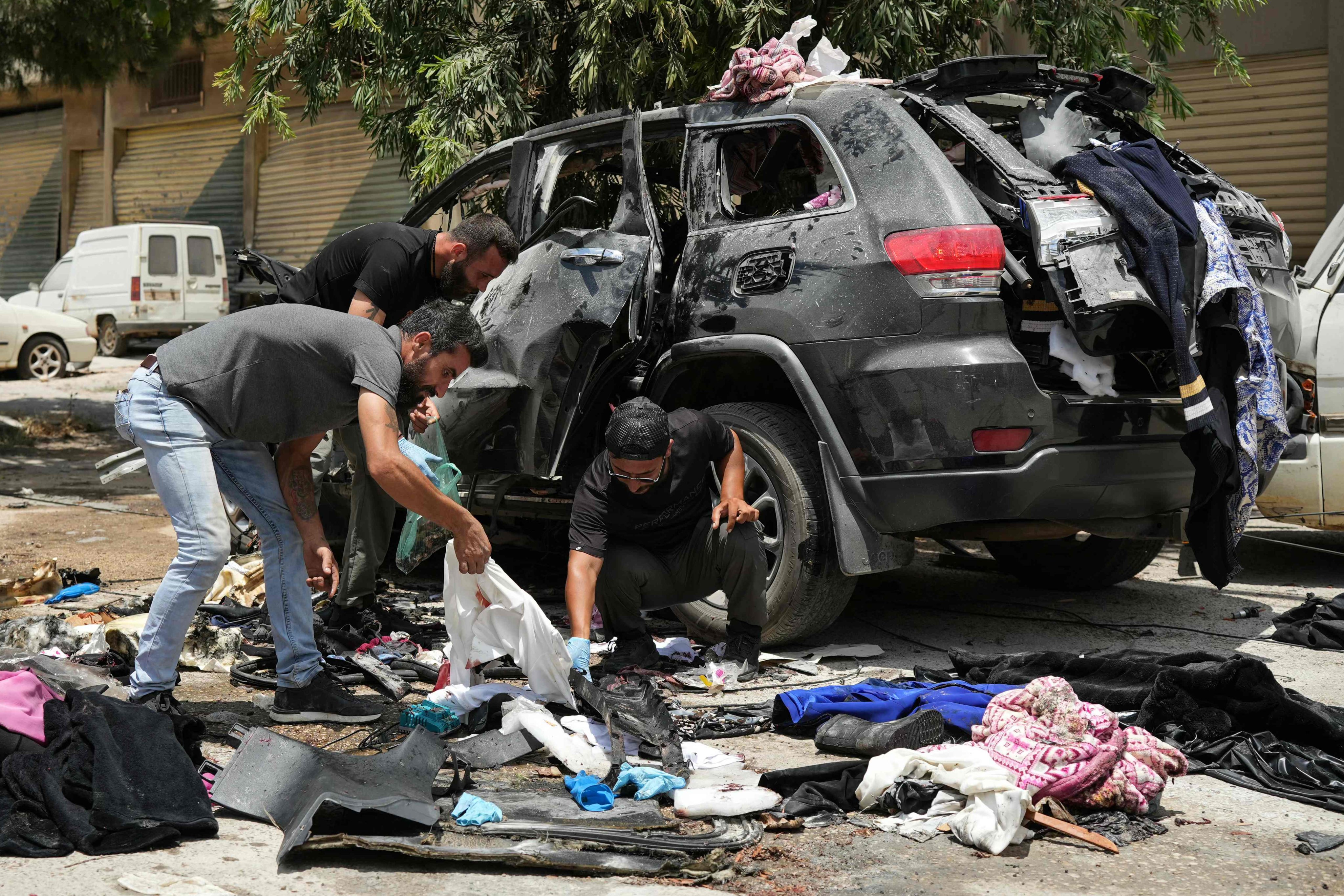 First responders inspect the wreckage of a car reportedly targeted by an Israeli strike in Nabatieh, Lebanon on Monday. Photo: AFP