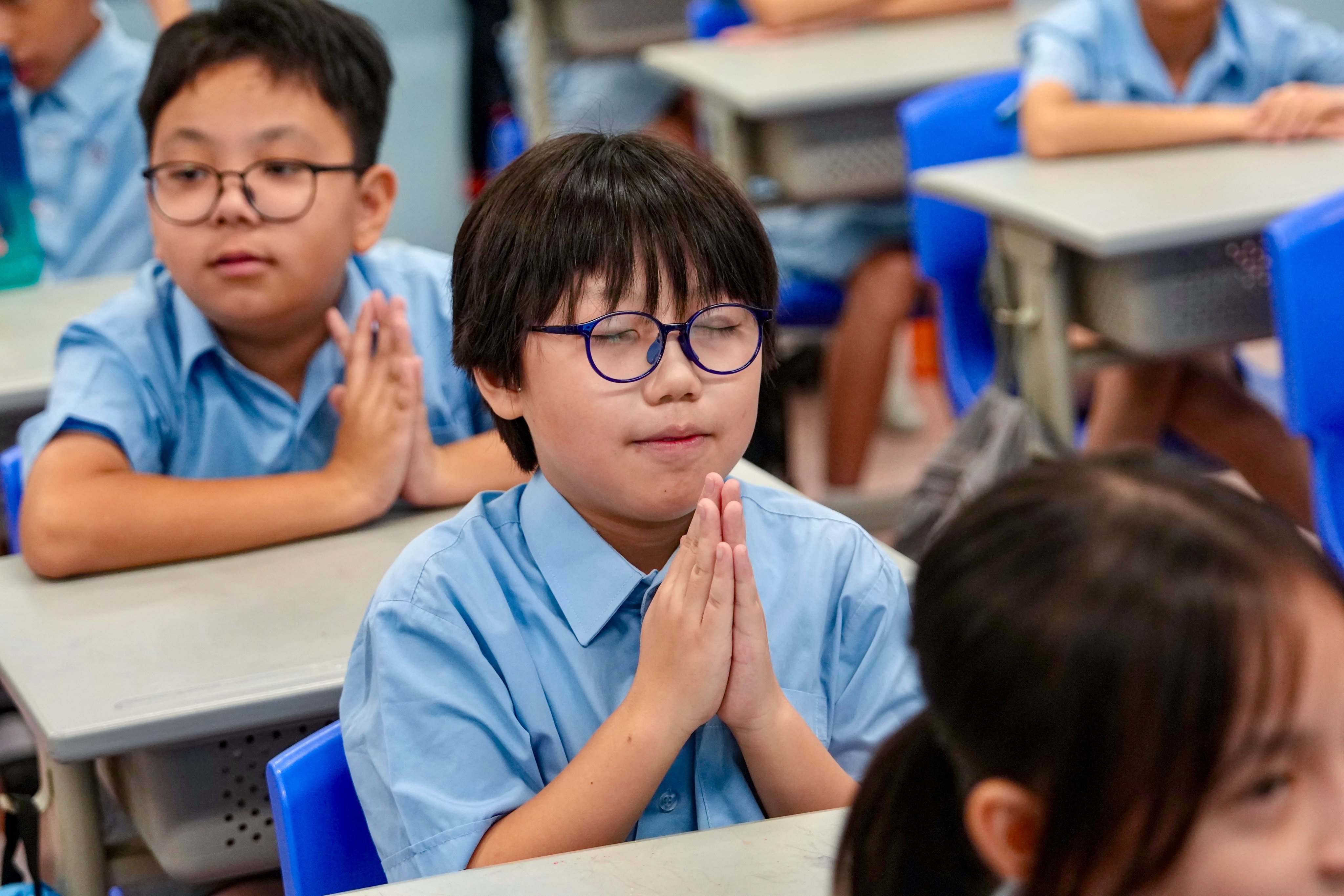 A pupil at Yaumati Catholic Primary School (Hoi Wang Road) prays in anticipation of his results. Photo: Sam Tsang