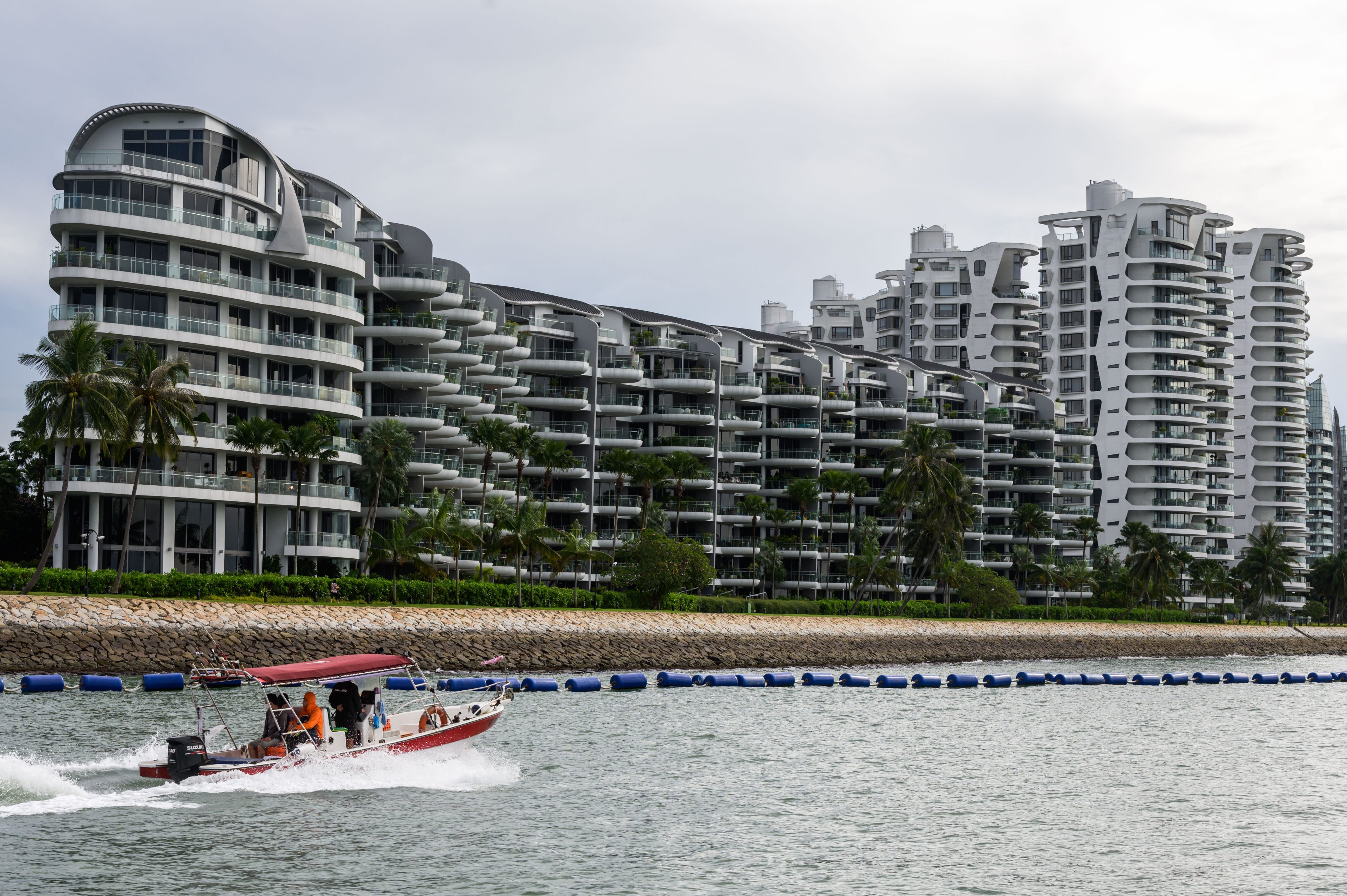 A small motor boat passes by luxury waterfront condominiums in Singapore’s Sentosa Cove. Photo: Getty Images