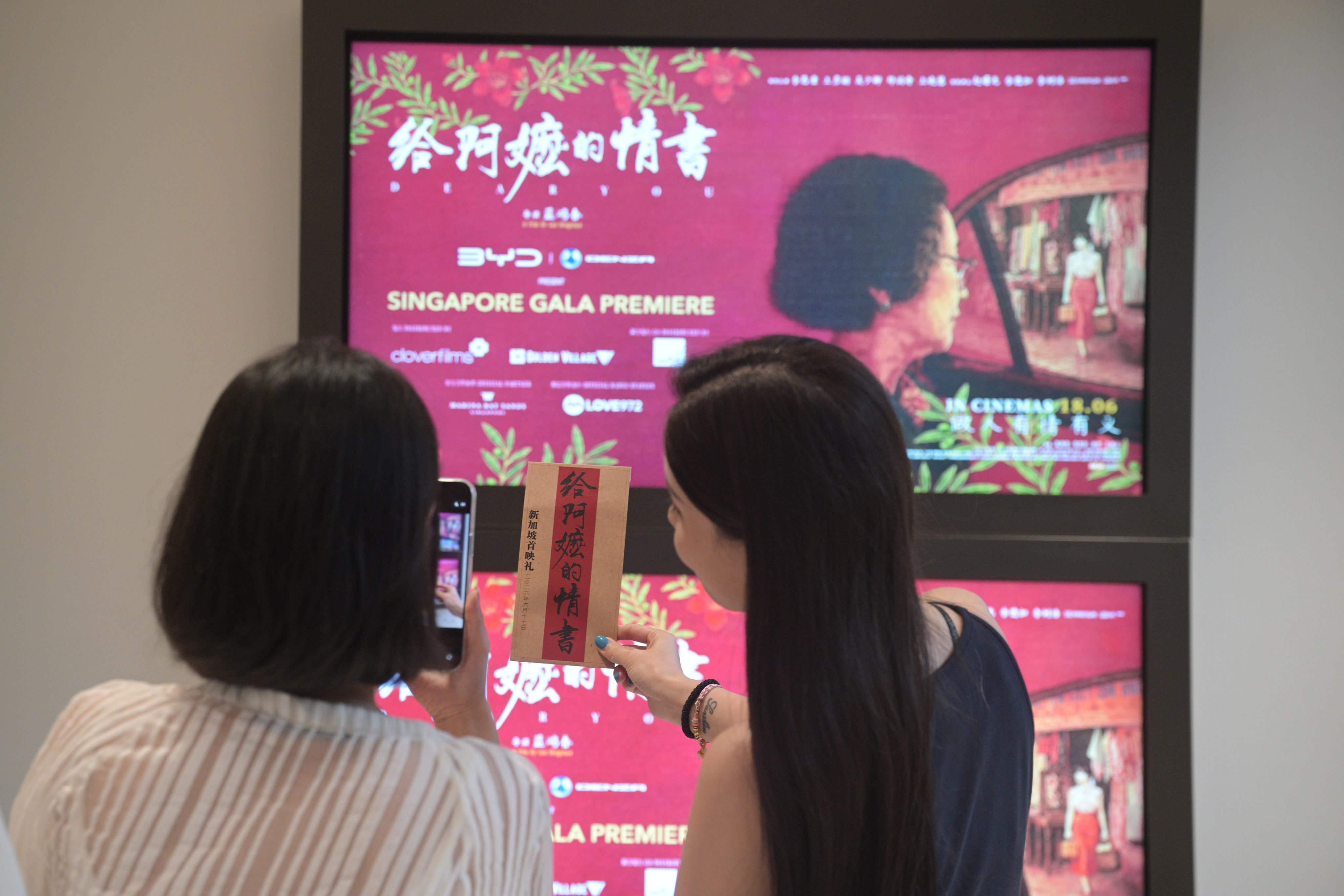Women take a photo with “Dear You” posters during its premiere in Singapore on June 17. Photo: Xinhua