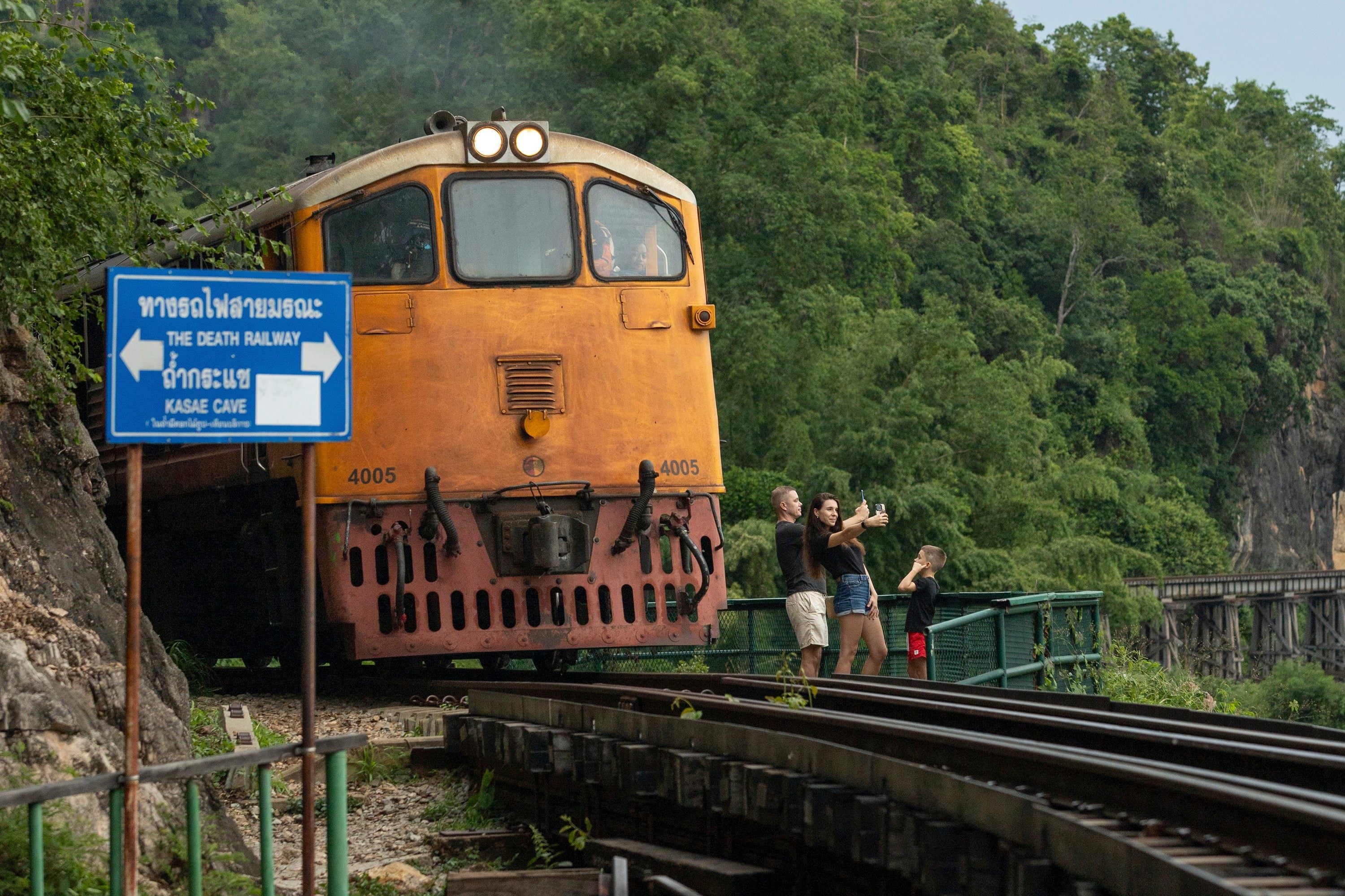 Tourists pose for photos as a train approaches Thamkra Sae station in Sai Yok, Thailand. Photo: AP