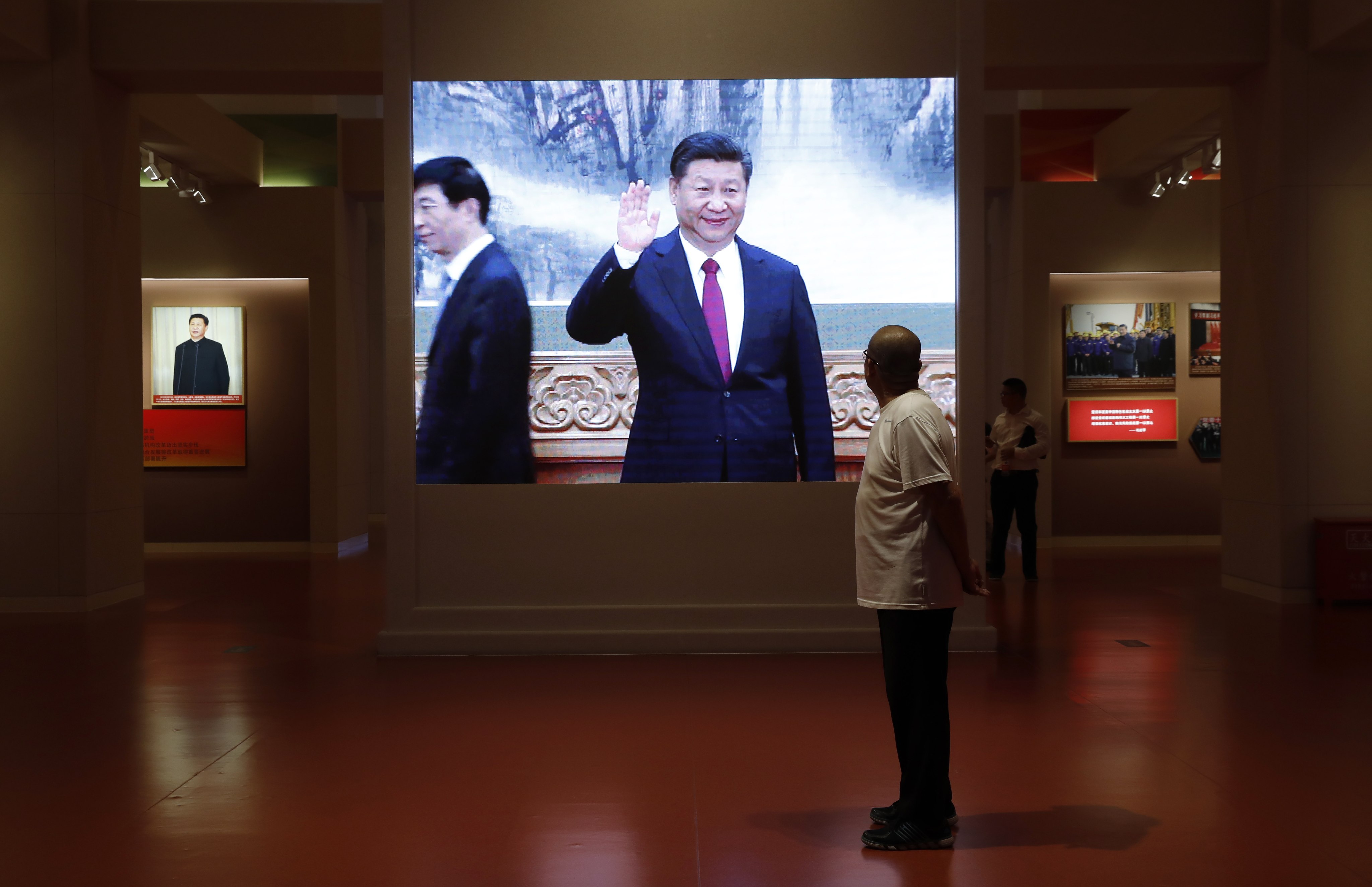 A visitor looks at a screen showing President Xi Jinping at an exhibition commemorating China’s Communist Party history and achievements, on October 1, 2019. Photo: EPA-EFE