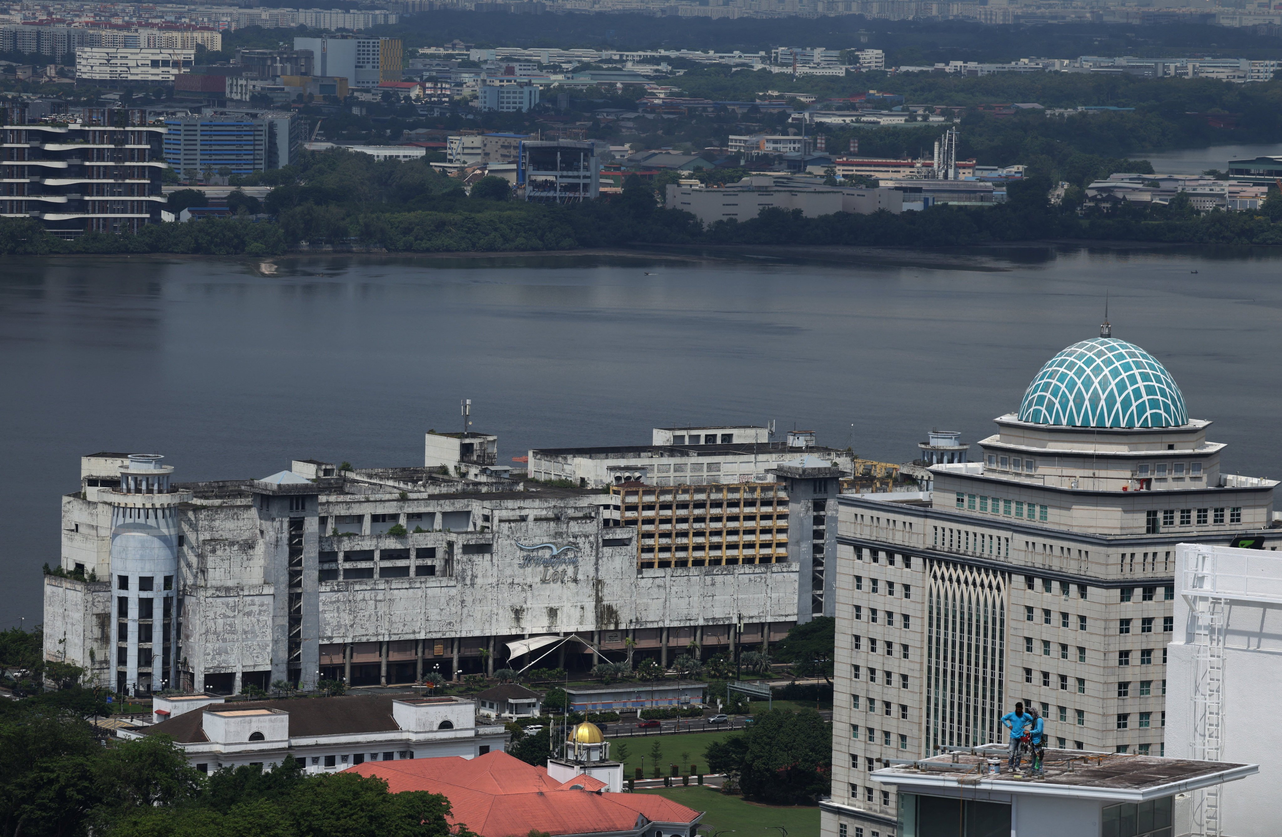 Workers repair a rooftop next to the Strait of Johor separating Singapore and Malaysia, in Johor Bahru, Malaysia on Monday. Photo: Reuters