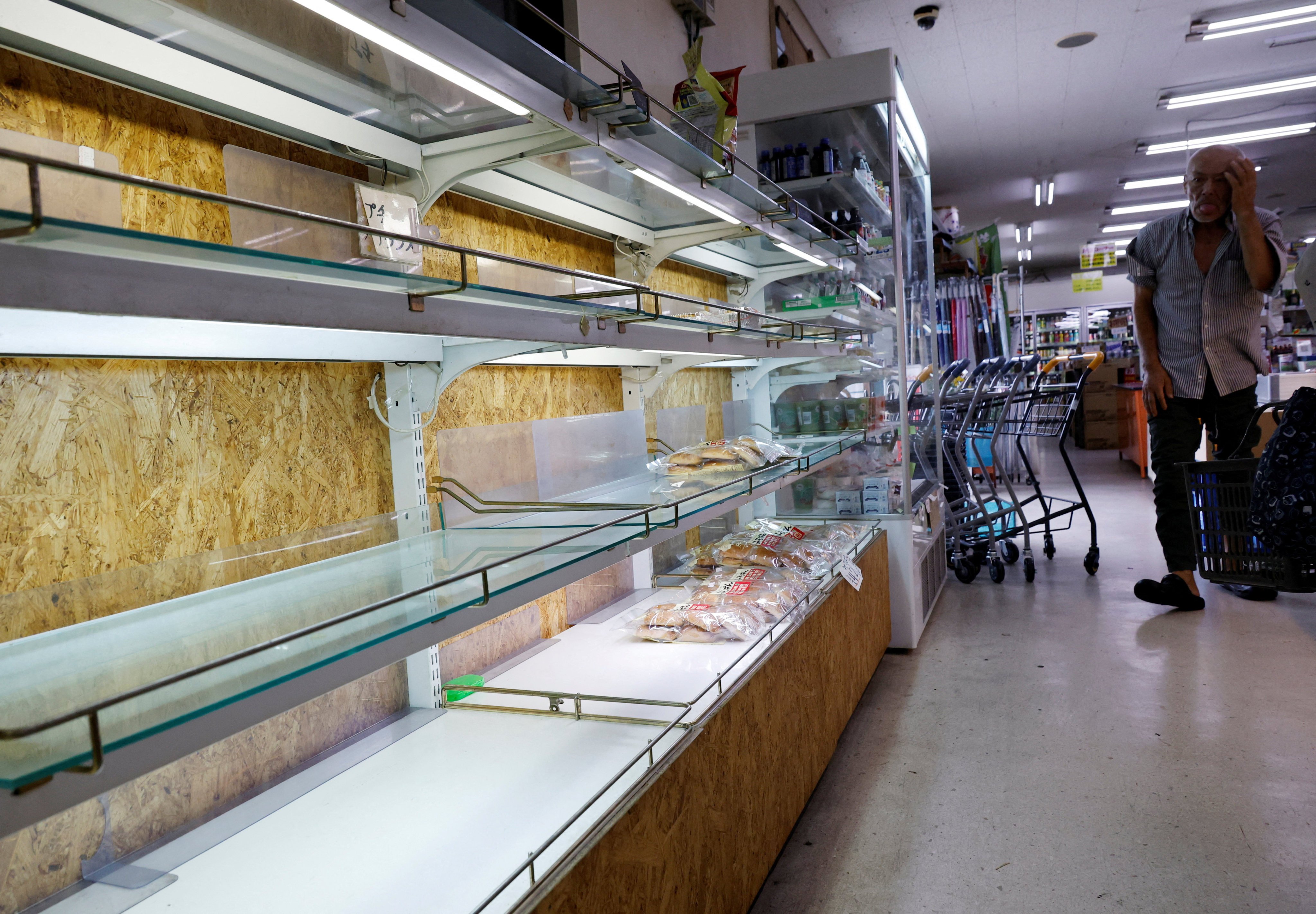 A man looks around the partly empty shelves of bread at a supermarket, as Super Typhoon Bavi approaches Ishigaki, Japan, on Friday. Photo: Reuters