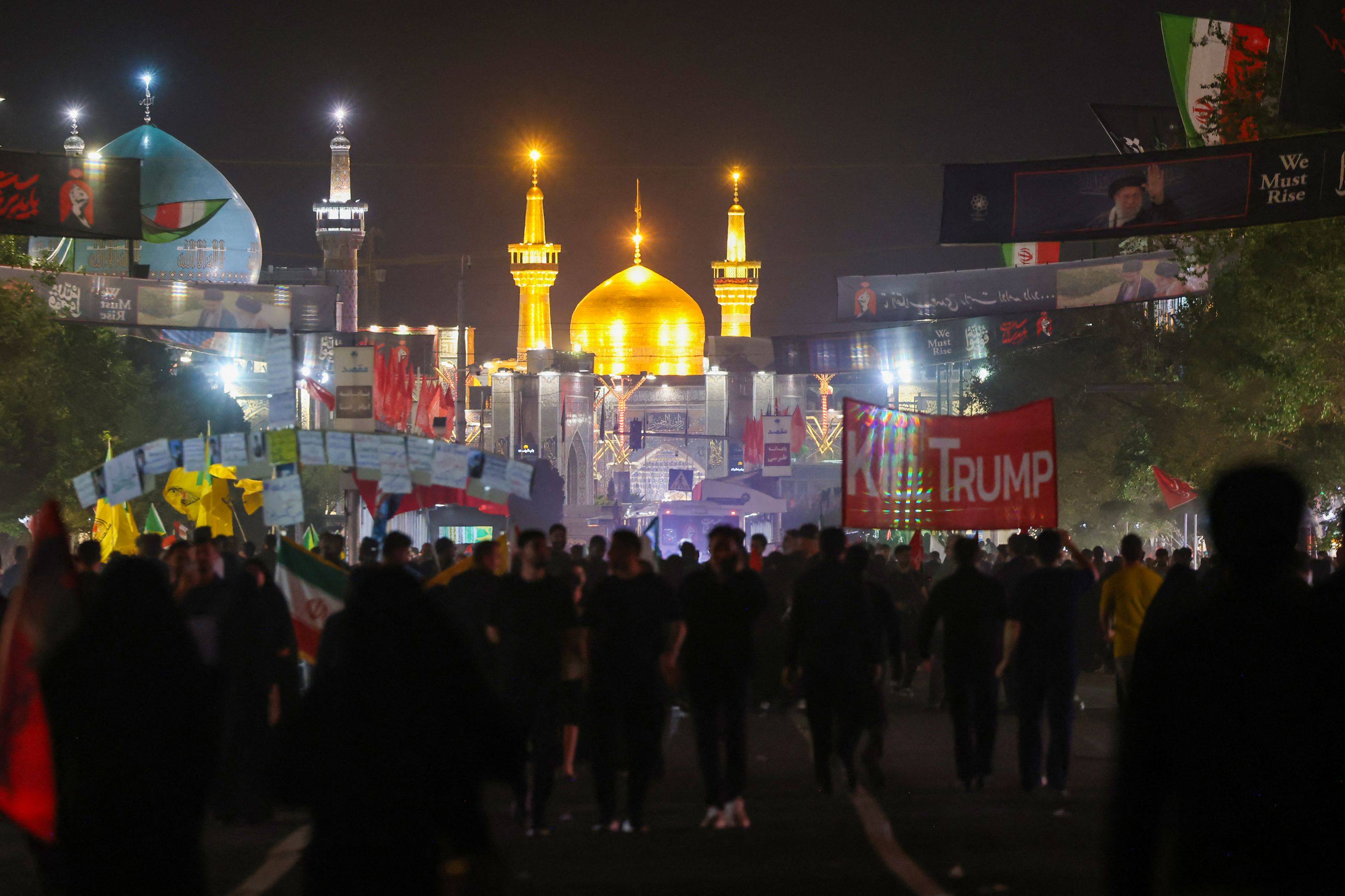 Mourners walk past an anti-US banner as they arrive for the funeral in Mashhad, Iran on Thursday. Photo: AFP