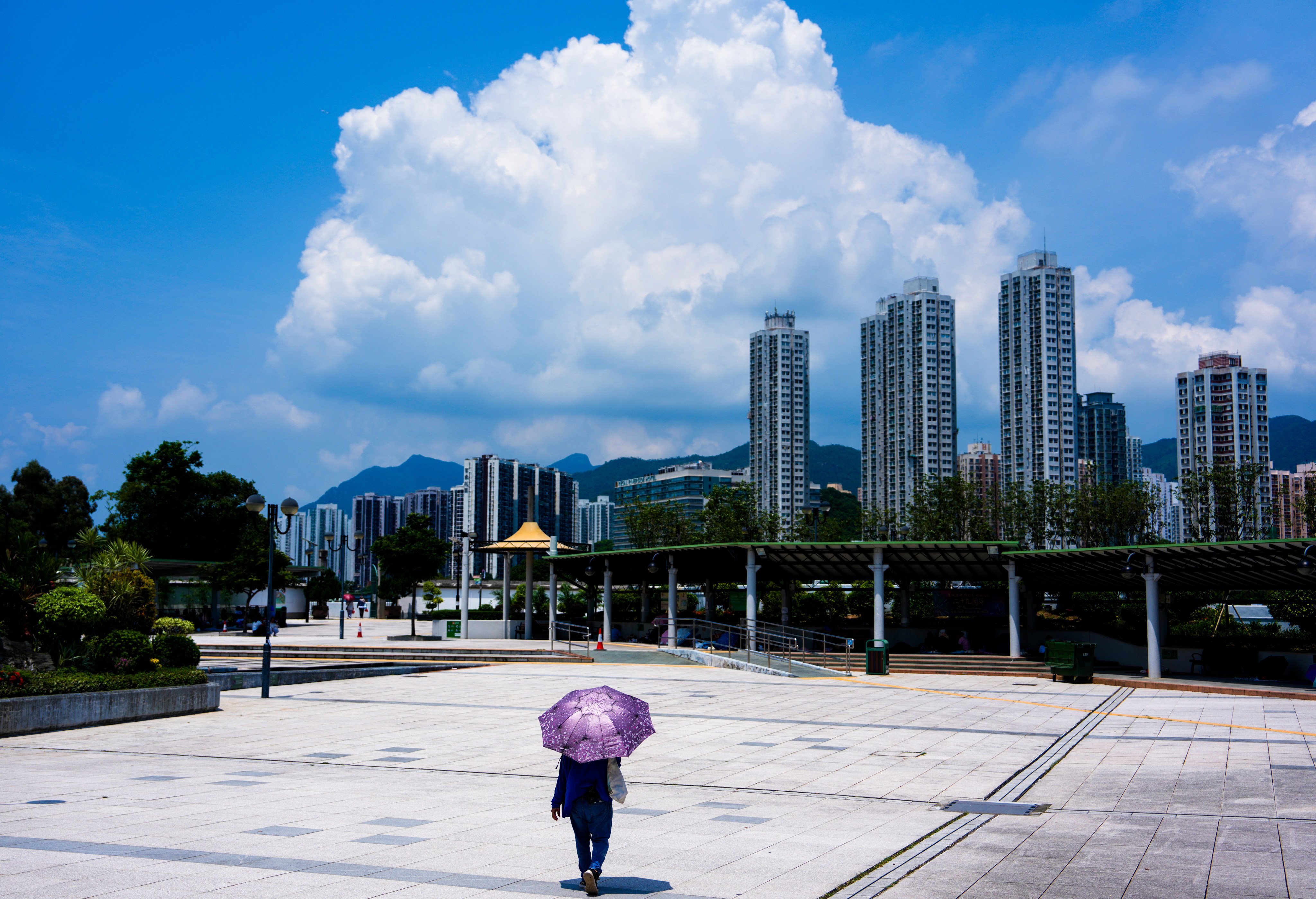 A lone pedestrian holds an umbrella to guard against the scorching sun in Sha Tin. The Observatory issued a “very hot weather” warning on Sunday due to the outer subsiding air of Typhoon Bavi, which made landfall in eastern China on Saturday night. Photo: Sam Tsang