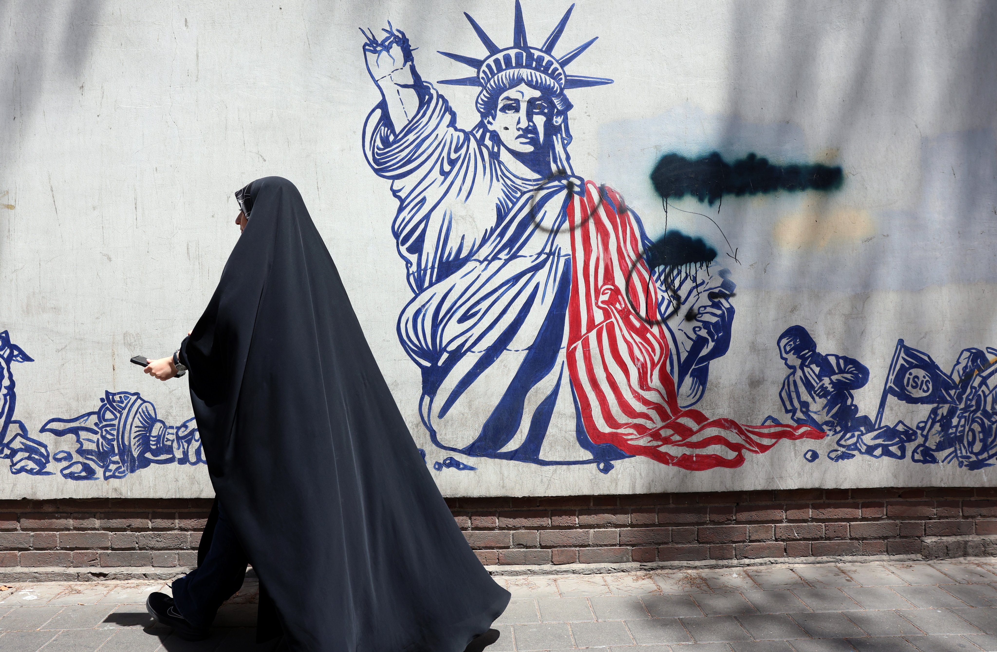 A woman walks past an anti-US mural next to the former US embassy in Tehran on Thursday. Photo: EPA