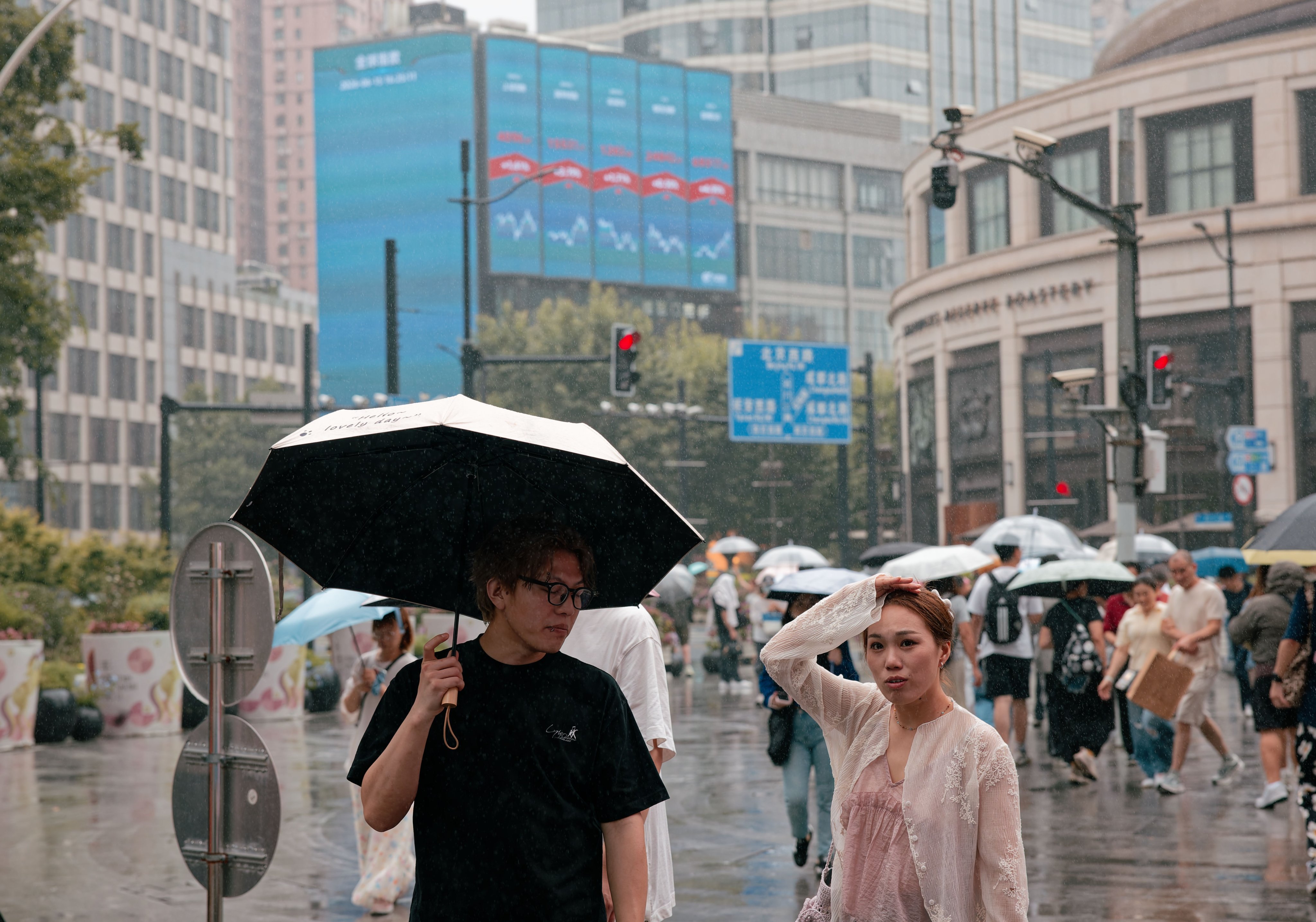 Pedestrians beneath a large screen showing the latest stock market and economic data in Shanghai on June 15. Photo: EPA