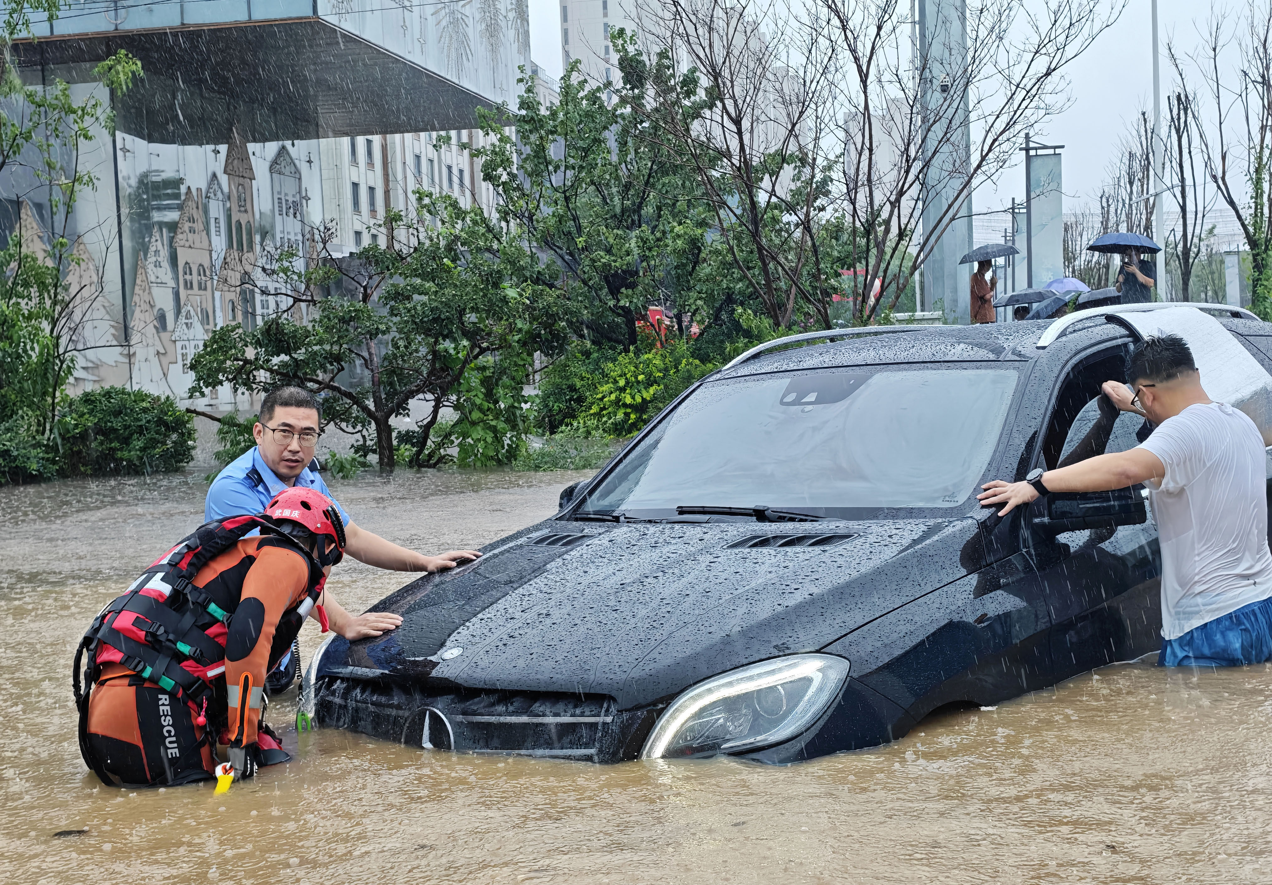 A police officer and firefighter help a driver whose car was stranded by the heavy rains in Shenyang, provincial capital of Liaoning in northeast China. Photo: Xinhua