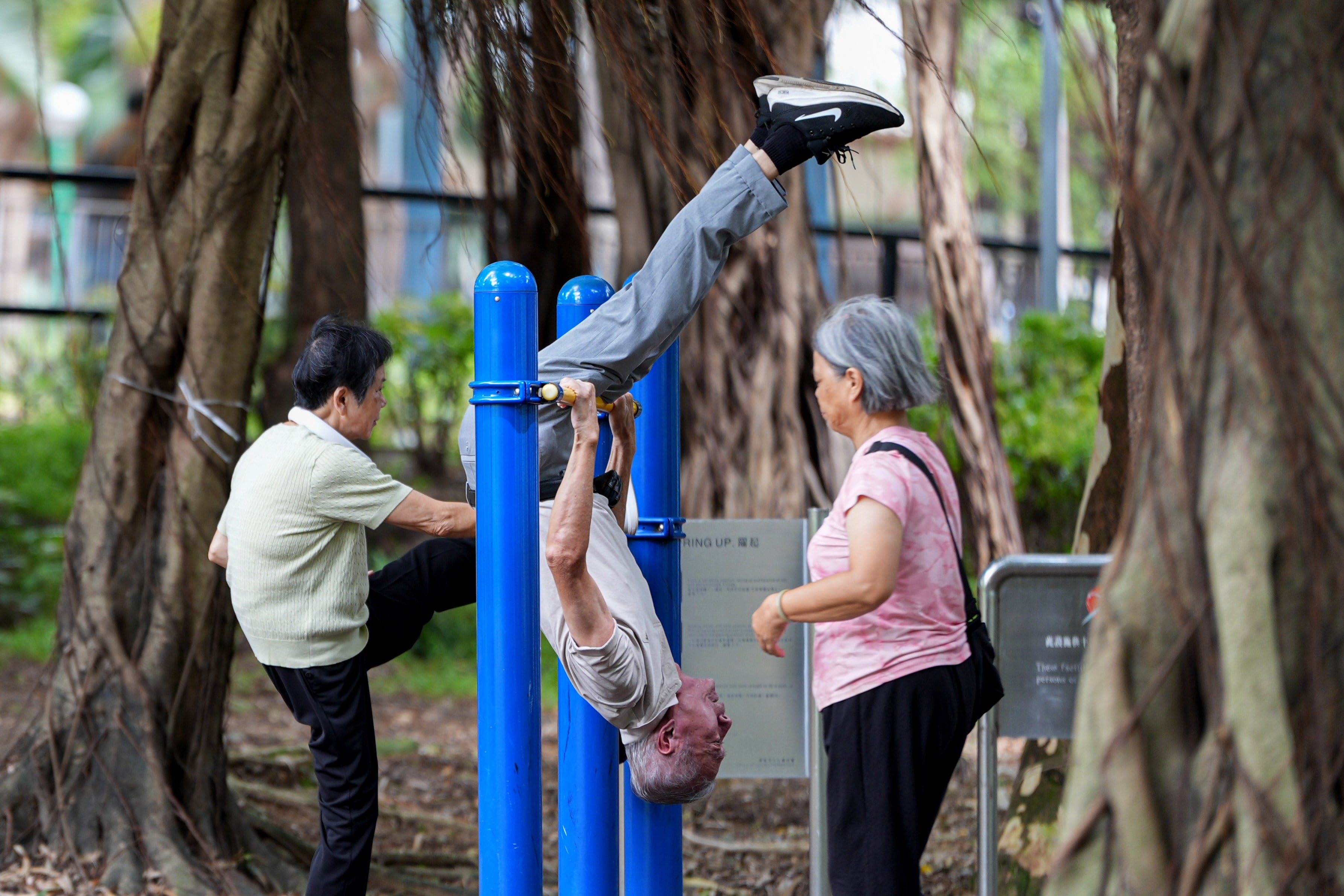An elderly man hangs upside down on a horizontal bar during his morning exercise in Fanling, Hong Kong. Photo: Eugene Lee
