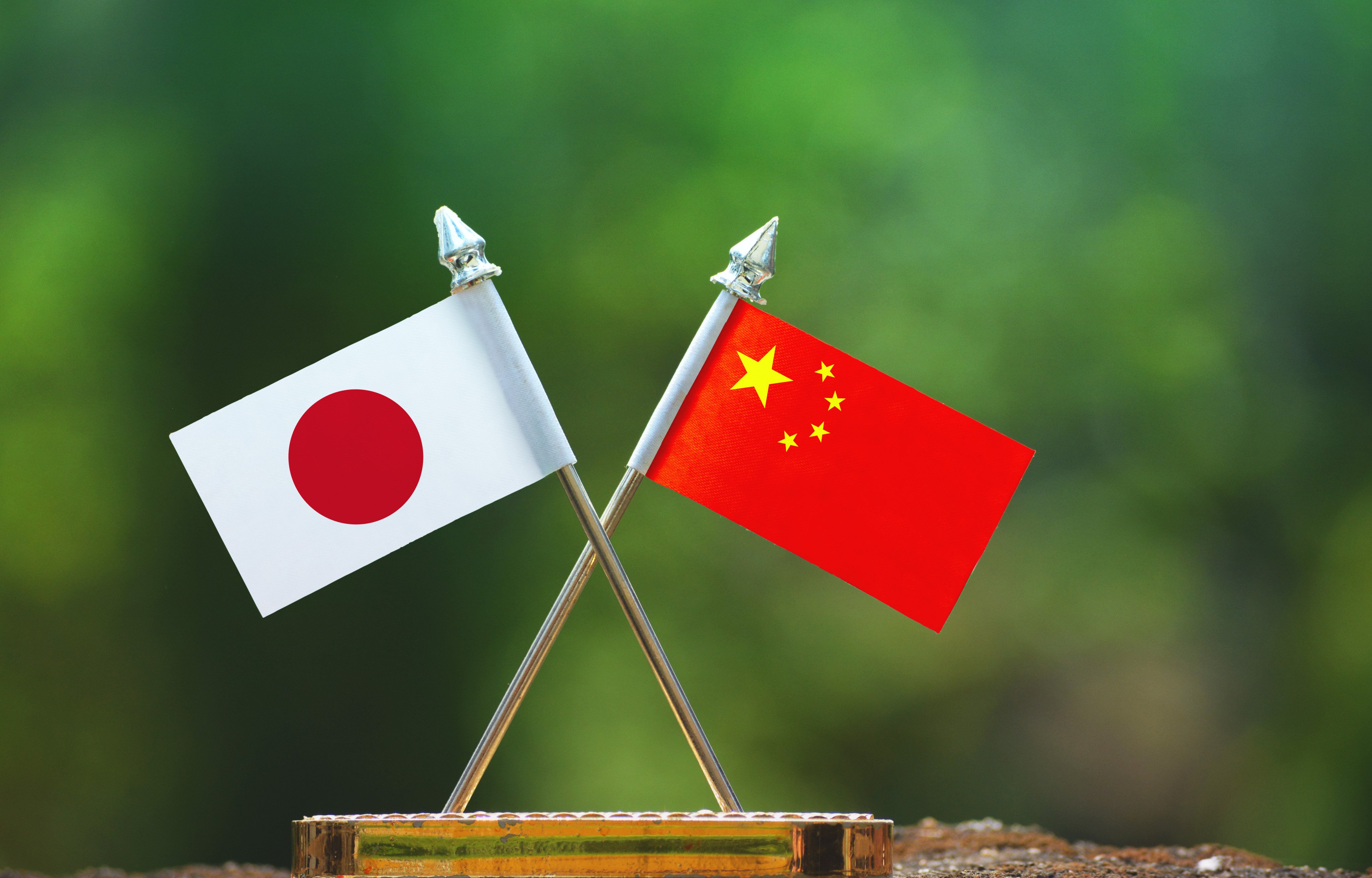 Asset id: 1075372364

China and Japan small flag with blur green background. Shutterstock Images