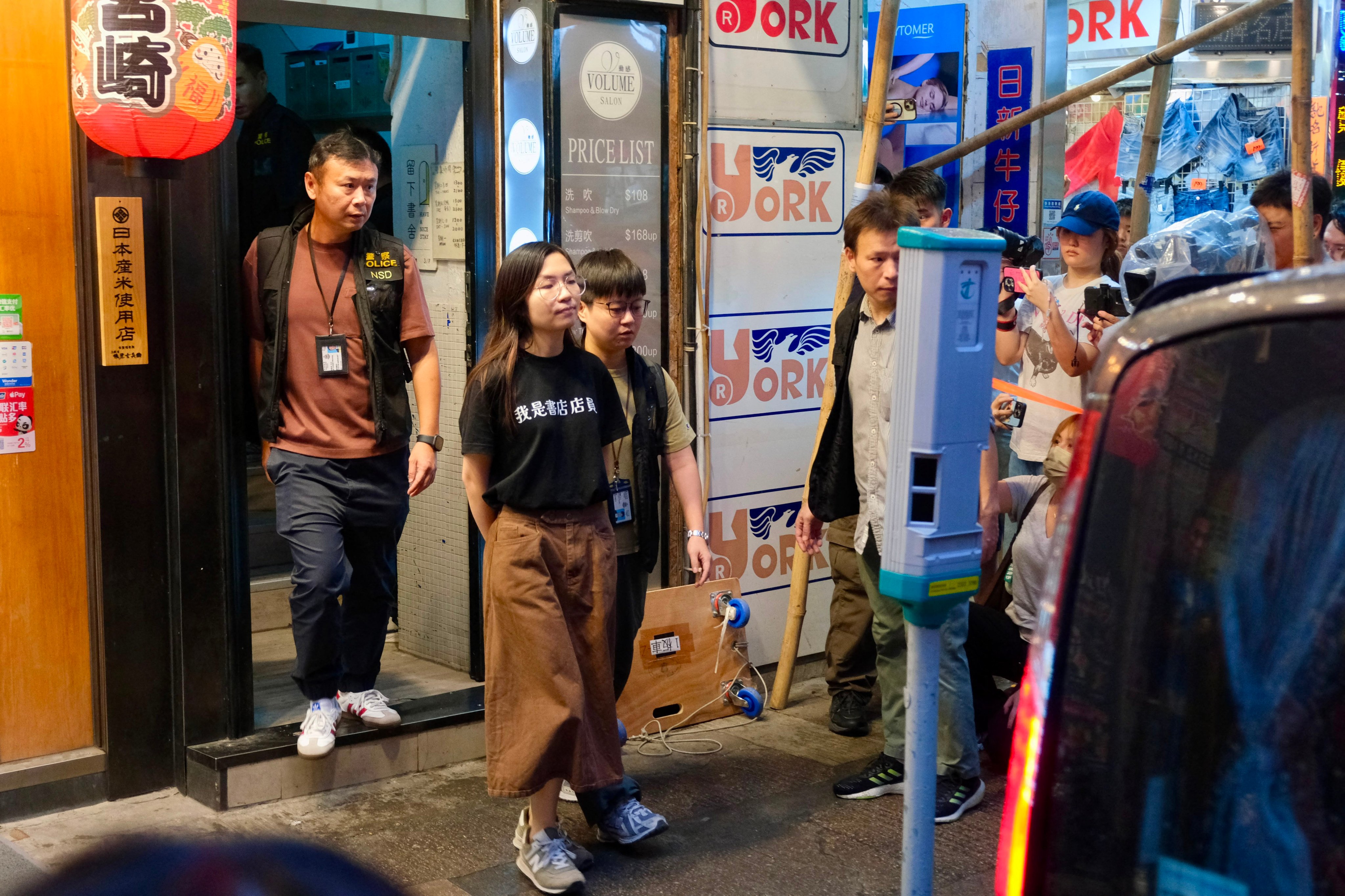 An independent bookstore employee is being led away by policemen after the officers raided the “Have A Nice Stay” bookshop and confiscated items in Hong Kong on July 15, 2026. (Photo by Tommy WANG / AFP)