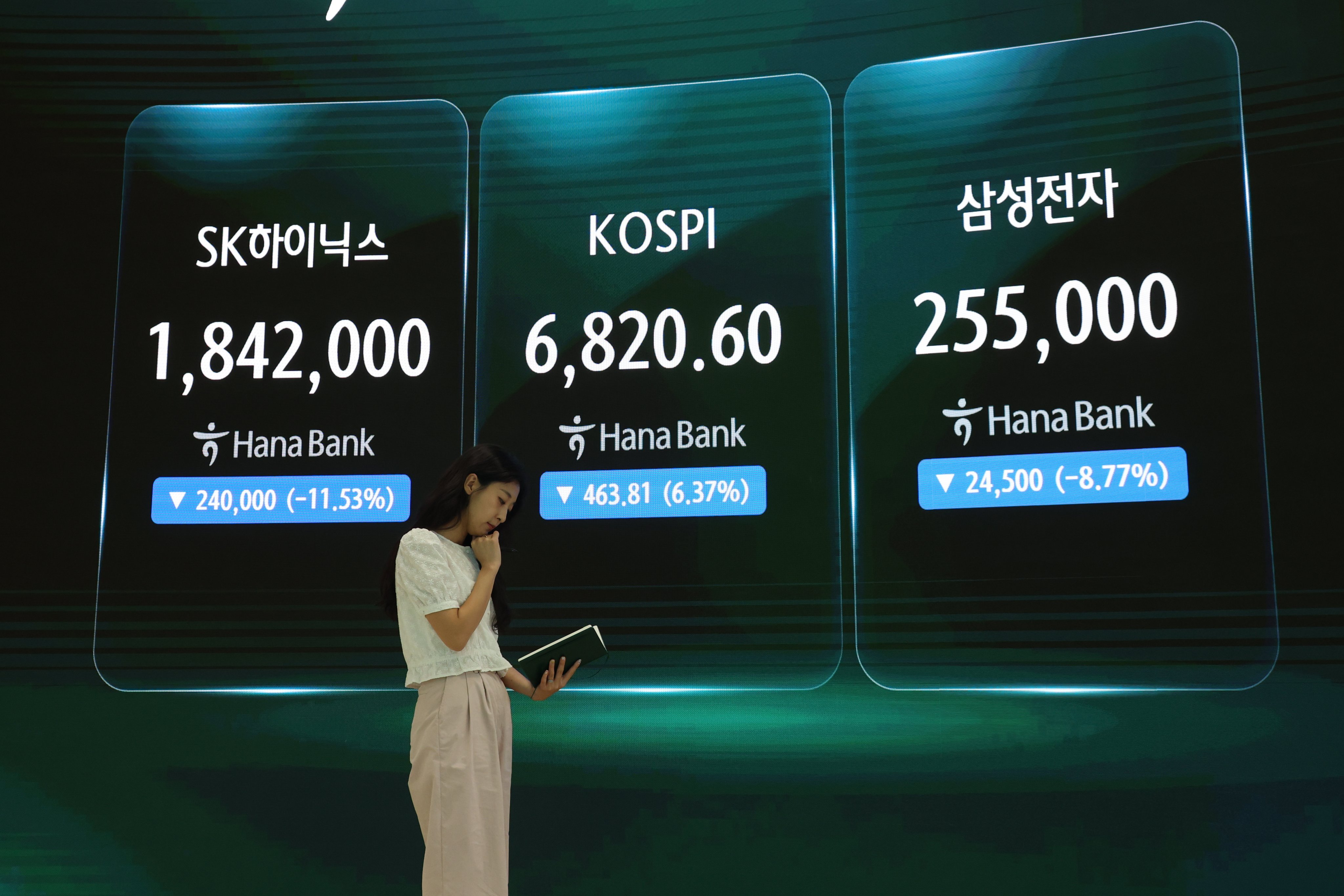 A woman is seen near an electronic signboard in the dealing room of Hana Bank in Seoul on Thursday. The Korea Composite Stock Price Index (Kospi) recently slid into a technical bear market. Photo: EPA