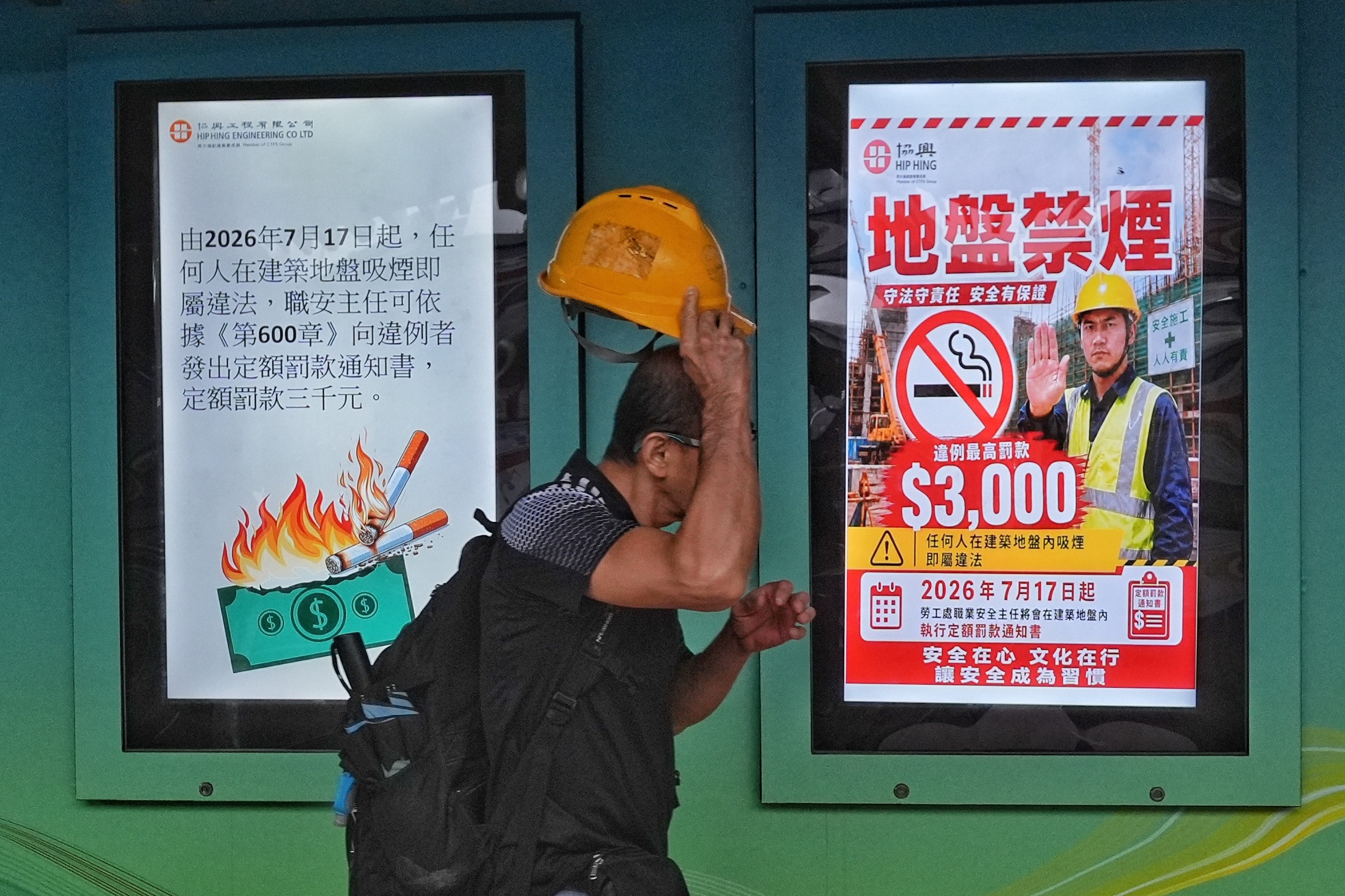 A worker walks past posters announcing Hong Kong’s new smoking ban on construction sites. Photo: Elson Li