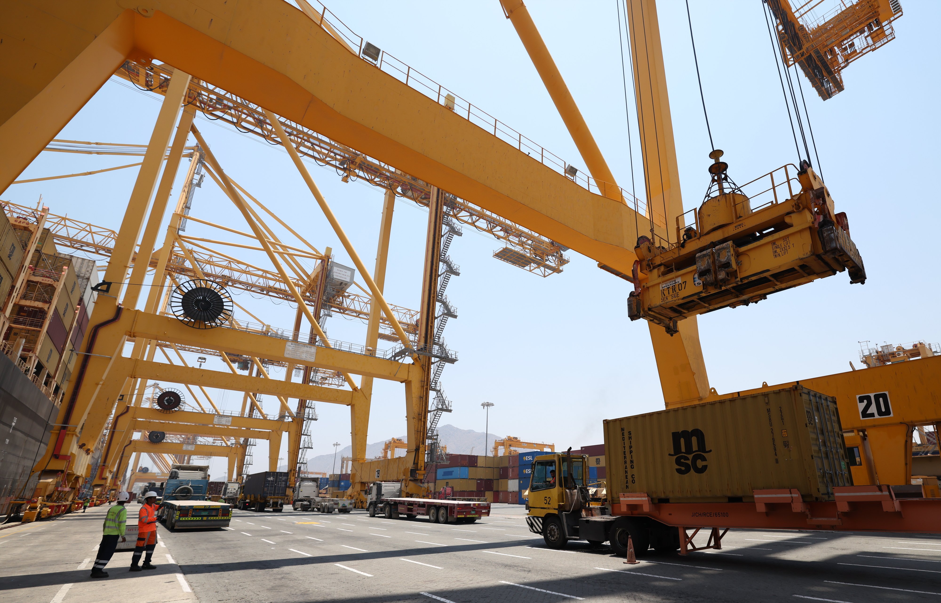 Workers load and unload containers  at Khor Fakkan Port in the United Arab Emirates on July 7. Photo: EPA
