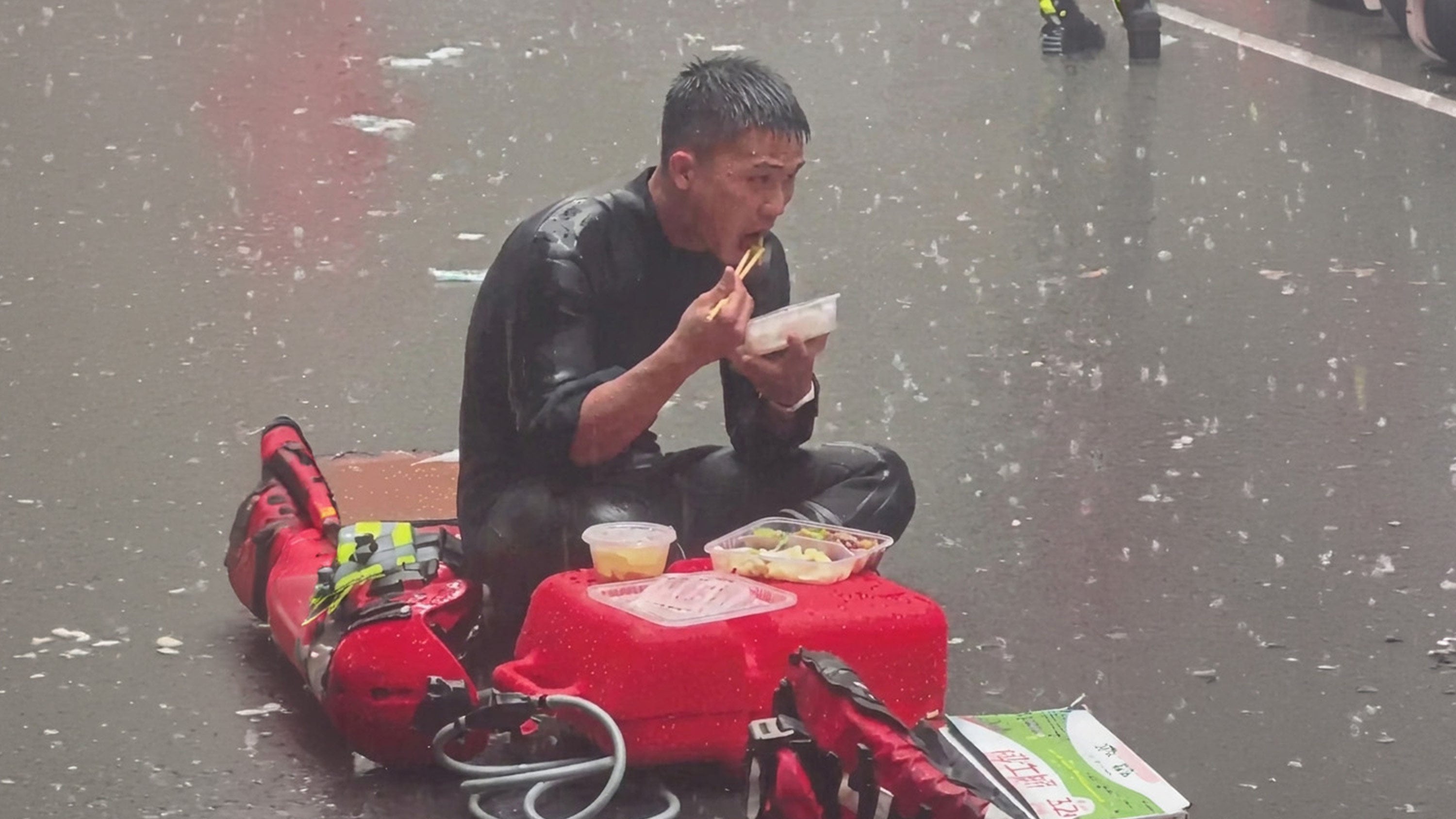 Guangdong firefighter, Liang Huan, grabs a quick meal in the pouring rain during severe flood relief operations in Guangxi. Photo: 163.com